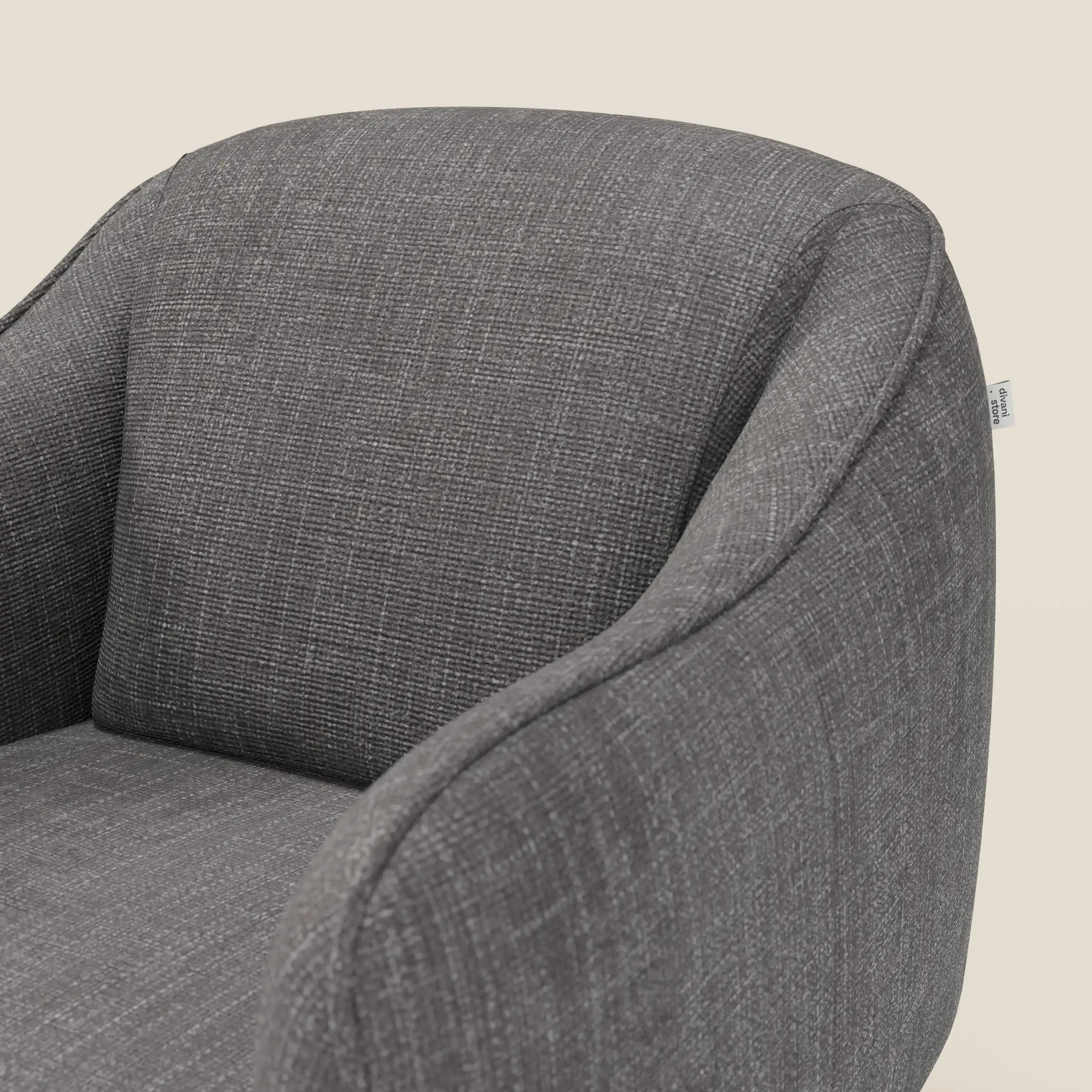 Un primo piano di Avela Poltroncina di Divani.Store, rivestita in morbido tessuto impermeabile T06 antracite, mostra lo schienale curvo, i braccioli arrotondati e la seduta liscia su uno sfondo beige chiaro per un look elegante.