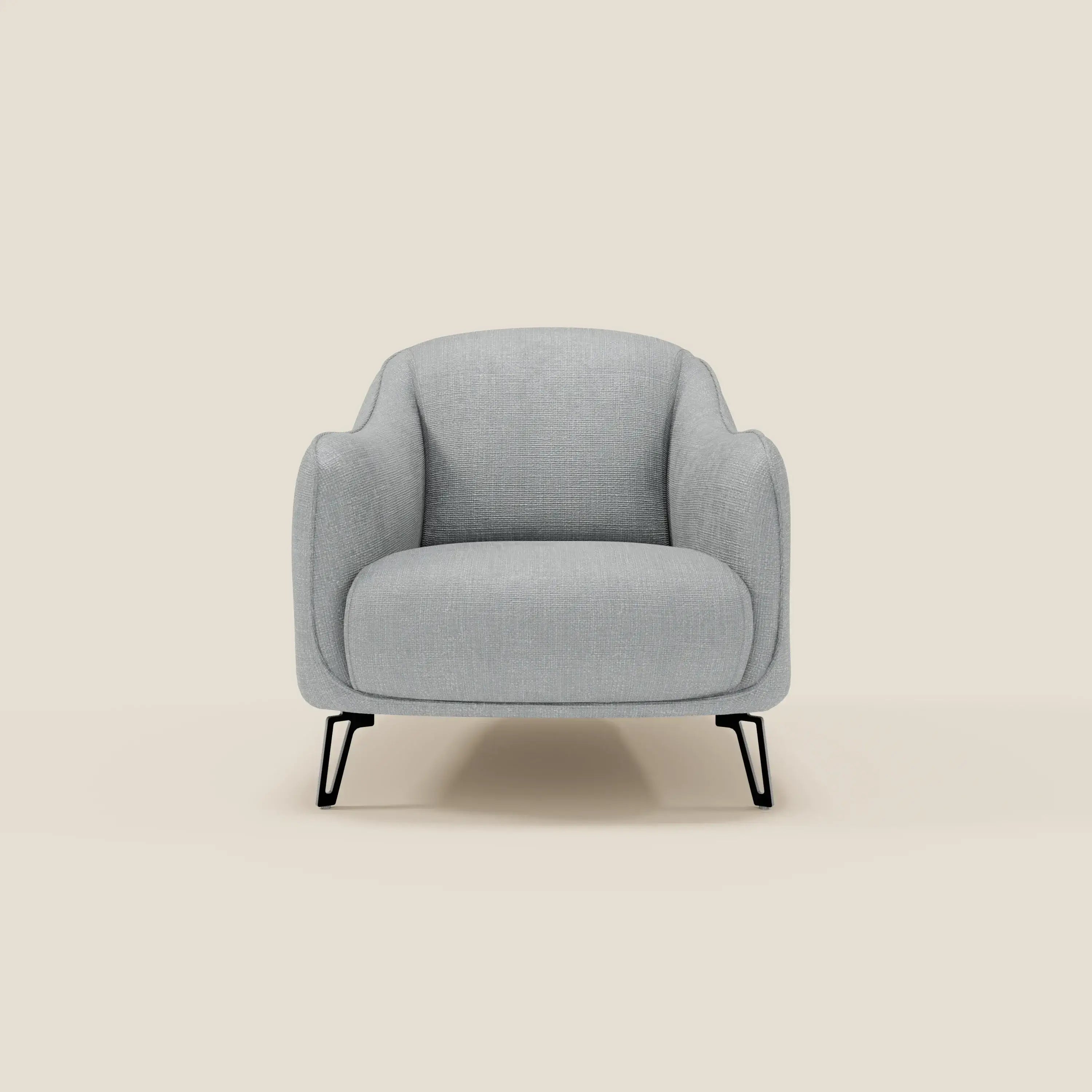 La Poltroncina Avela di Divani.Store, in morbido tessuto impermeabile T06 ghiaccio, ha bordi arrotondati, gambe in metallo nero, seduta imbottita, schienale curvo e braccioli leggermente svasati su sfondo beige.