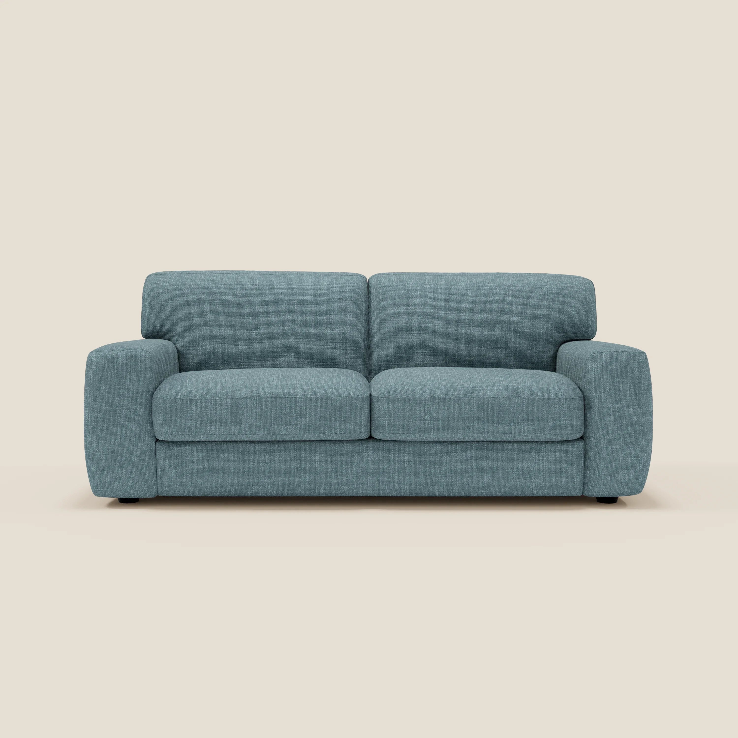 Il letto materasso Cloud Divano H17 cm di Divani.Store, in tessuto impermeabile T06 azzurro, è caratterizzato da cuscini morbidi, braccioli arrotondati e piedini neri, che offrono un comfort quotidiano su uno sfondo beige semplice.