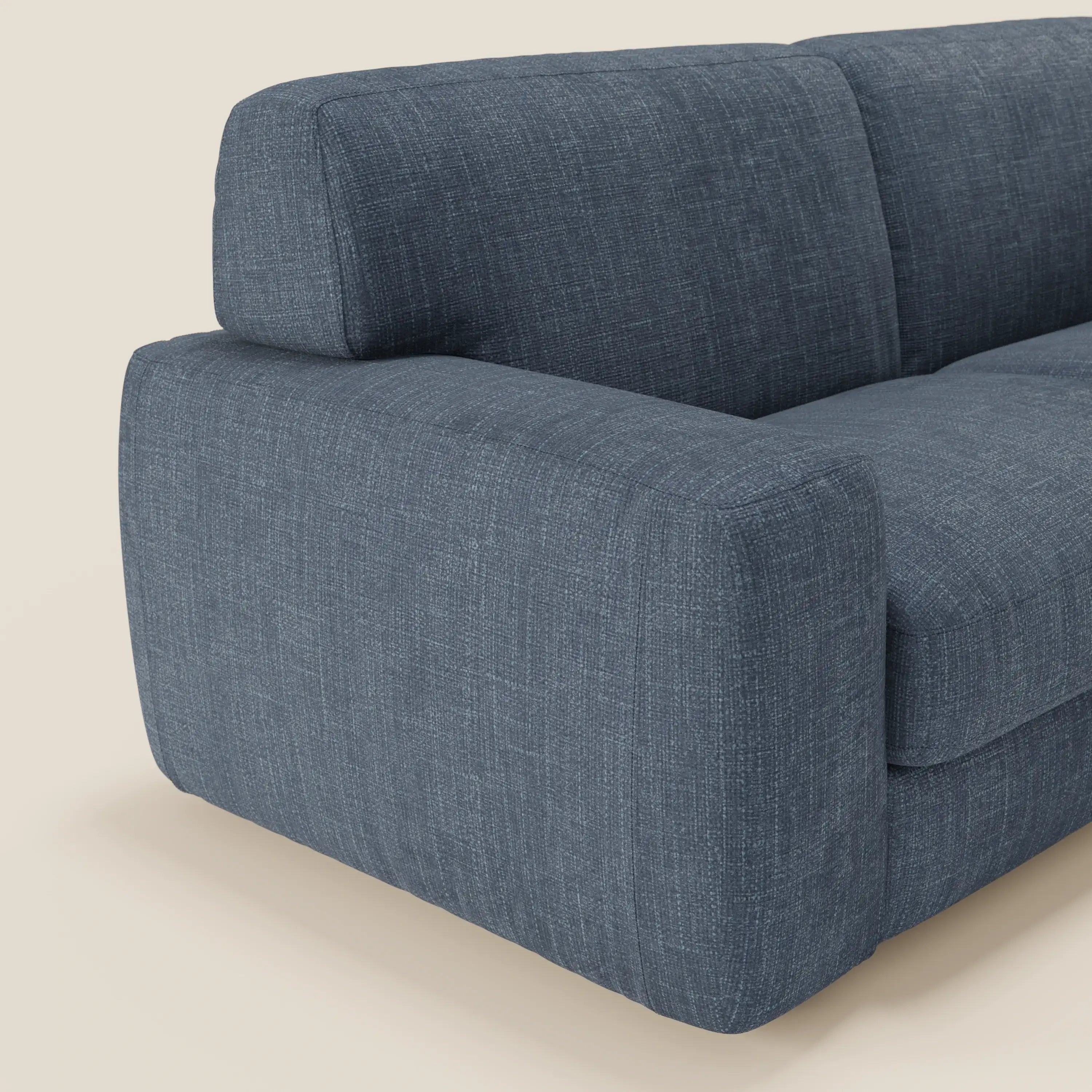 Un primo piano di Cloud Divano letto materasso H17 cm di Divani.Store mostra i morbidi cuscini in tessuto impermeabile T06 blu e gli spessi braccioli, che spiccano su uno sfondo beige chiaro con design compatto e linee pulite.