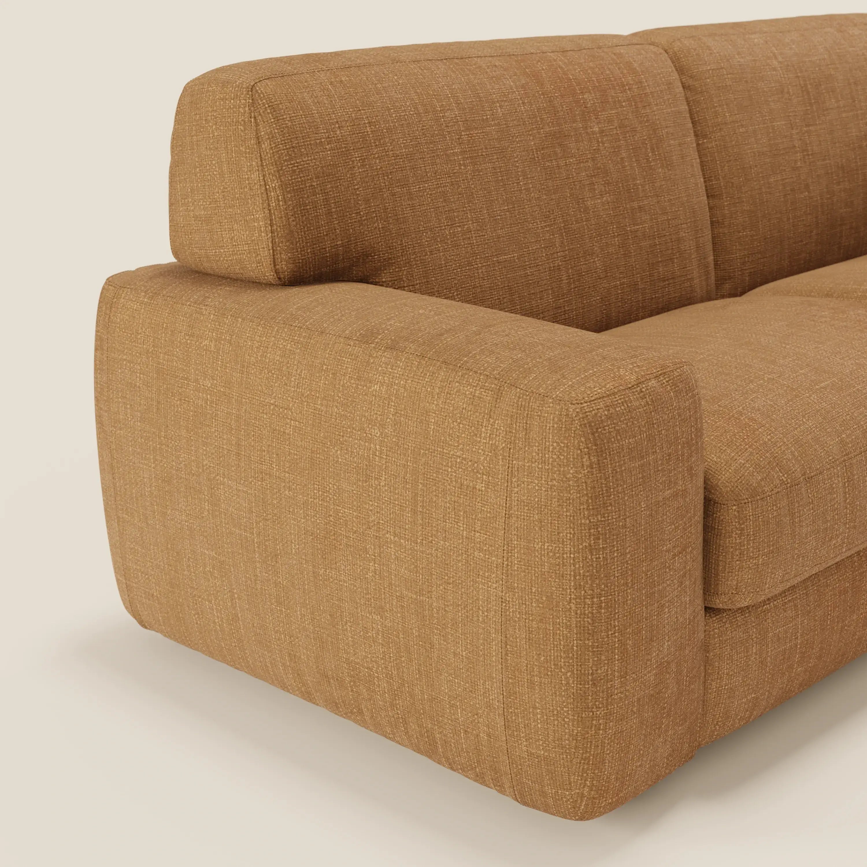 Un primo piano del letto materasso Cloud Divano H17 cm dai morbidi cuscini in tessuto impermeabile T06 ocra di Divani.Store, che mostra il suo design felpato e squadrato e lo stile minimal in ocra chiaro su uno sfondo bianco sporco.