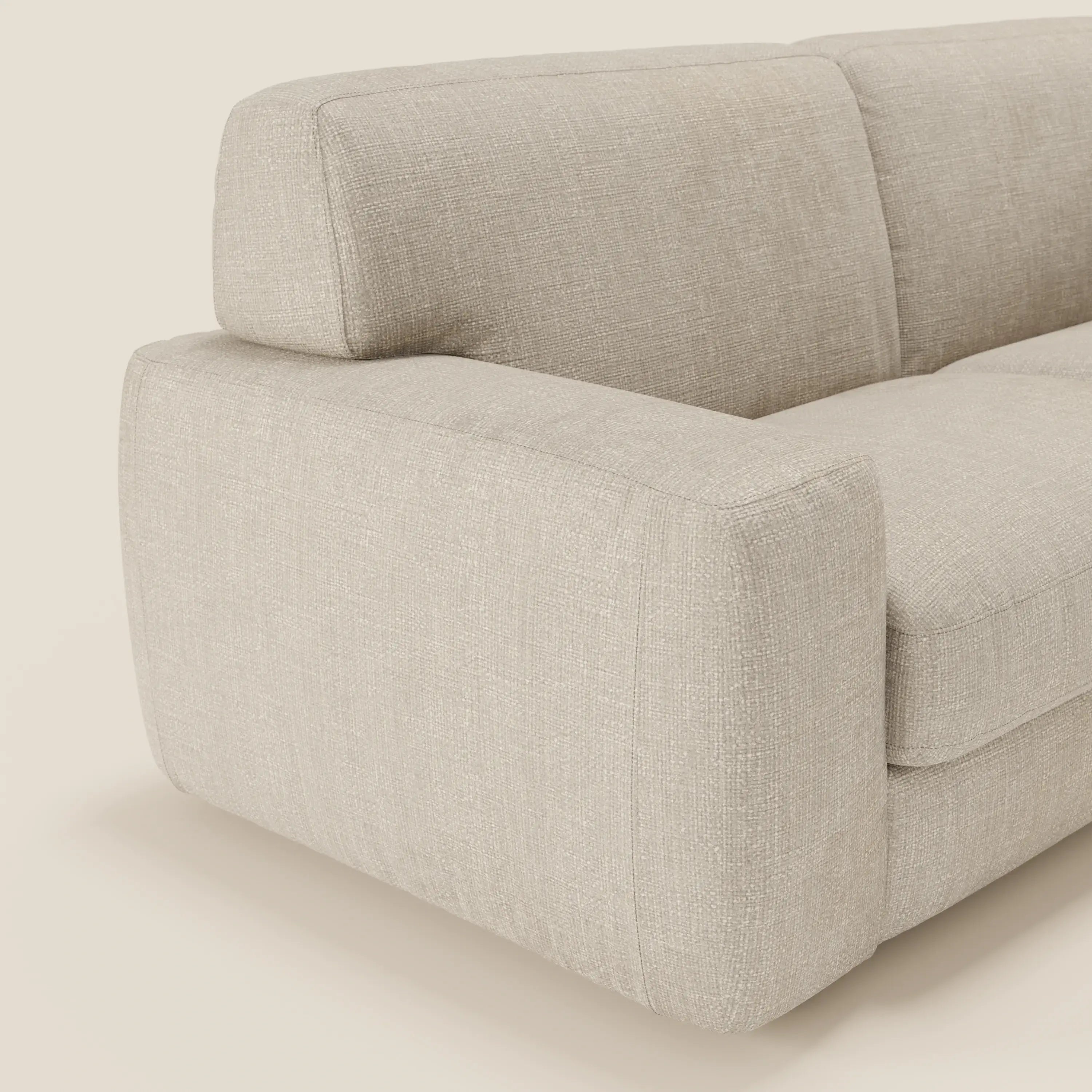 Un primo piano del divano letto materasso Cloud H17 cm di Divani.Store mostra gli spessi braccioli squadrati e i morbidi cuscini in panna T06, impermeabili, che offrono un comfort quotidiano e un look morbido e moderno su uno sfondo neutro.