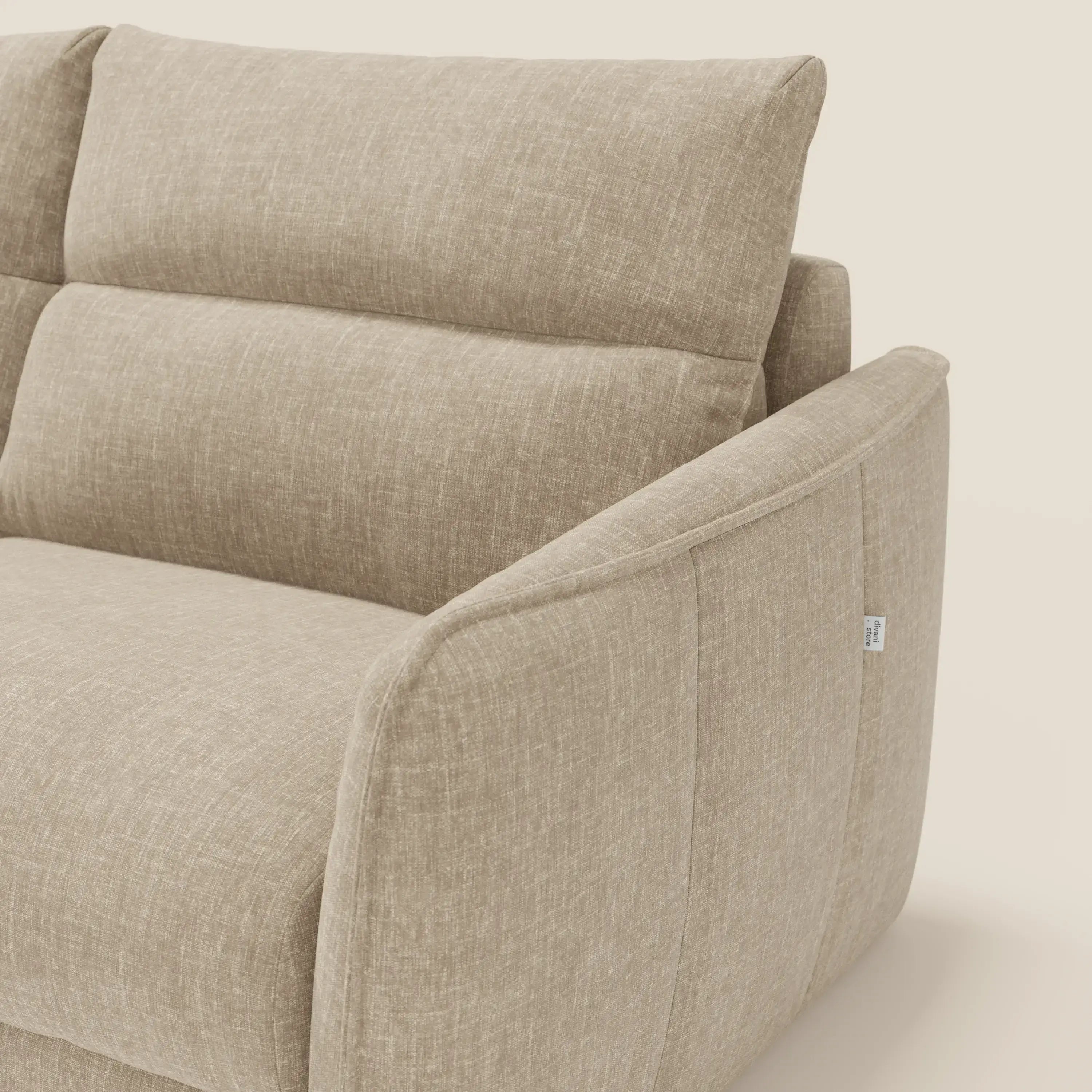 Primo piano di Elios Divano letto di Divani.Store in tessuto smacchiabile T24 beige, caratterizzato da schienale alto e imbottito, seduta profonda, braccioli morbidi, rivestimento a trama sottile e una piccola etichetta bianca sulla cucitura laterale.