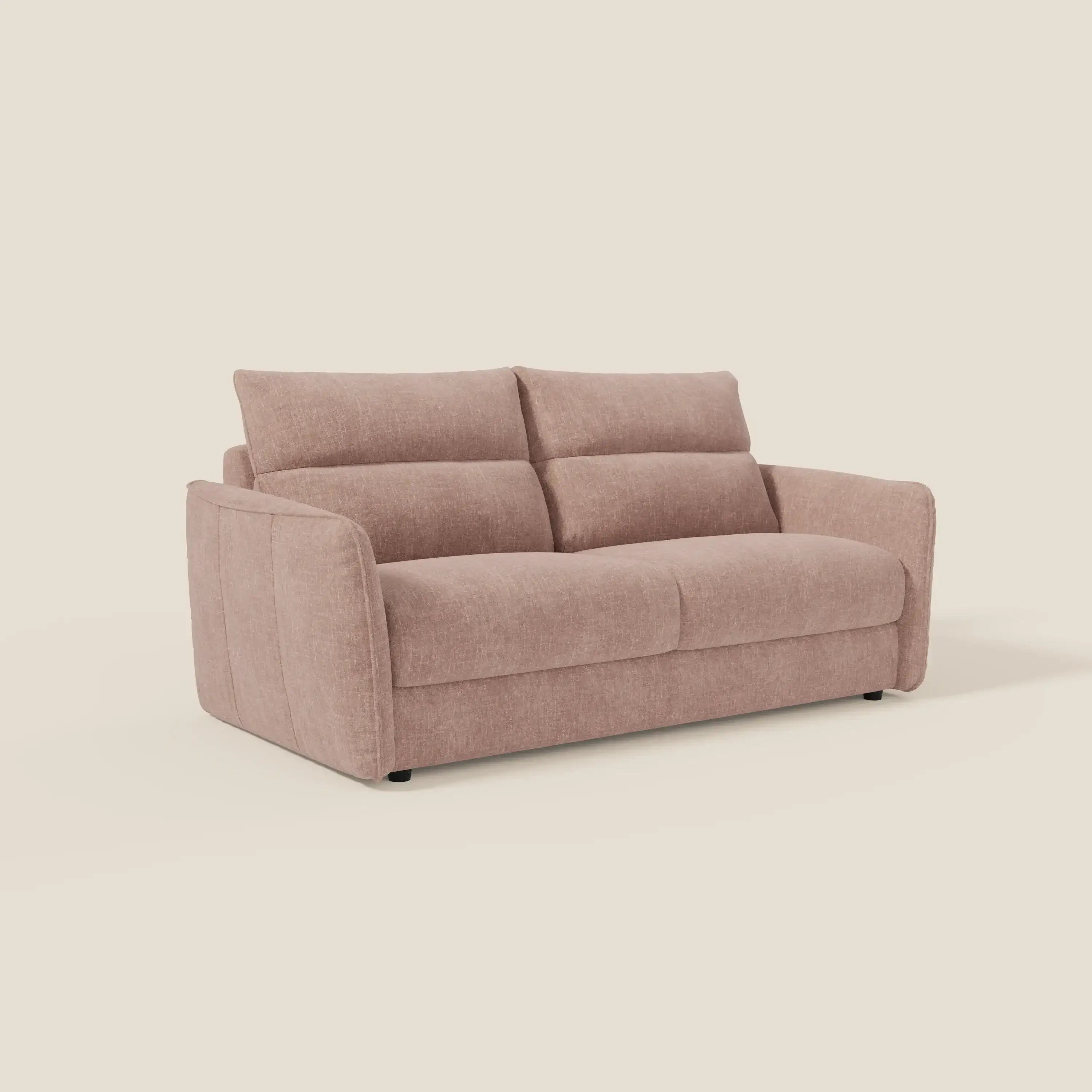 Il divano letto Elios di Divani.Store è caratterizzato da un tessuto smacchiabile T24 color rosa blush, da ampie sedute imbottite, da soffici cuscini angolari per lo schienale, da morbidi braccioli arrotondati e da sottili dettagli di cucitura, il tutto su uno sfondo beige chiaro.