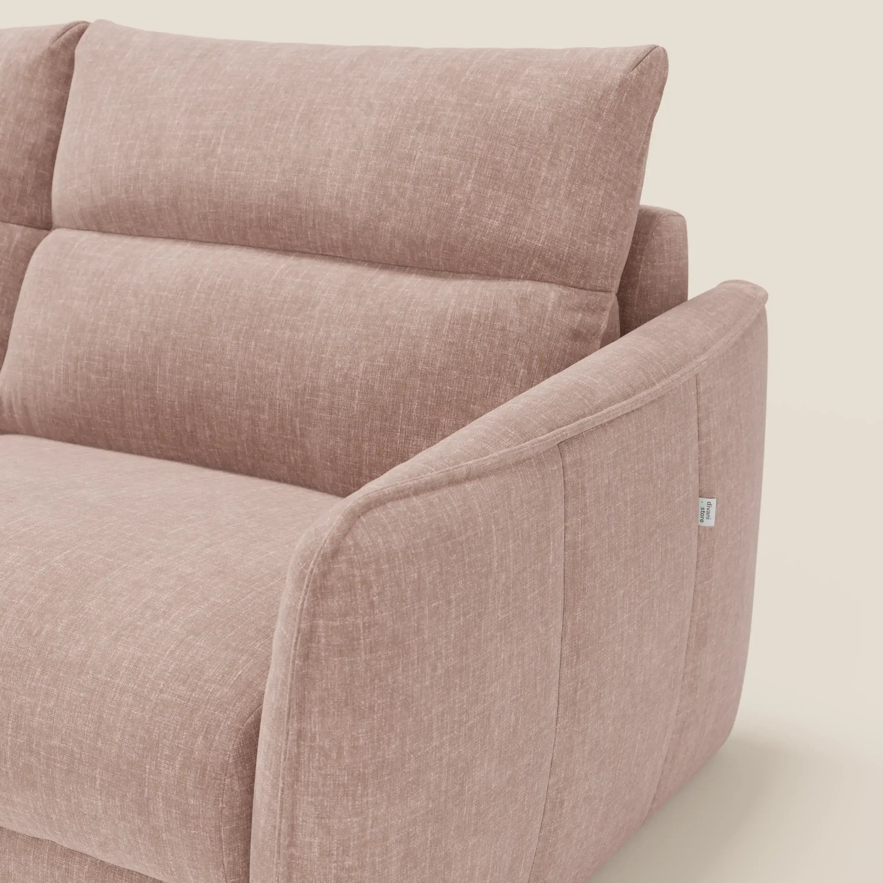 Un primo piano del Divano letto Elios di Divani.Store, caratterizzato da morbidi cuscini in spalliera e braccioli in T24 rosa cipria tessuto smacchiabile, mostra il suo tessuto strutturato e le sottili cuciture su uno sfondo beige chiaro.