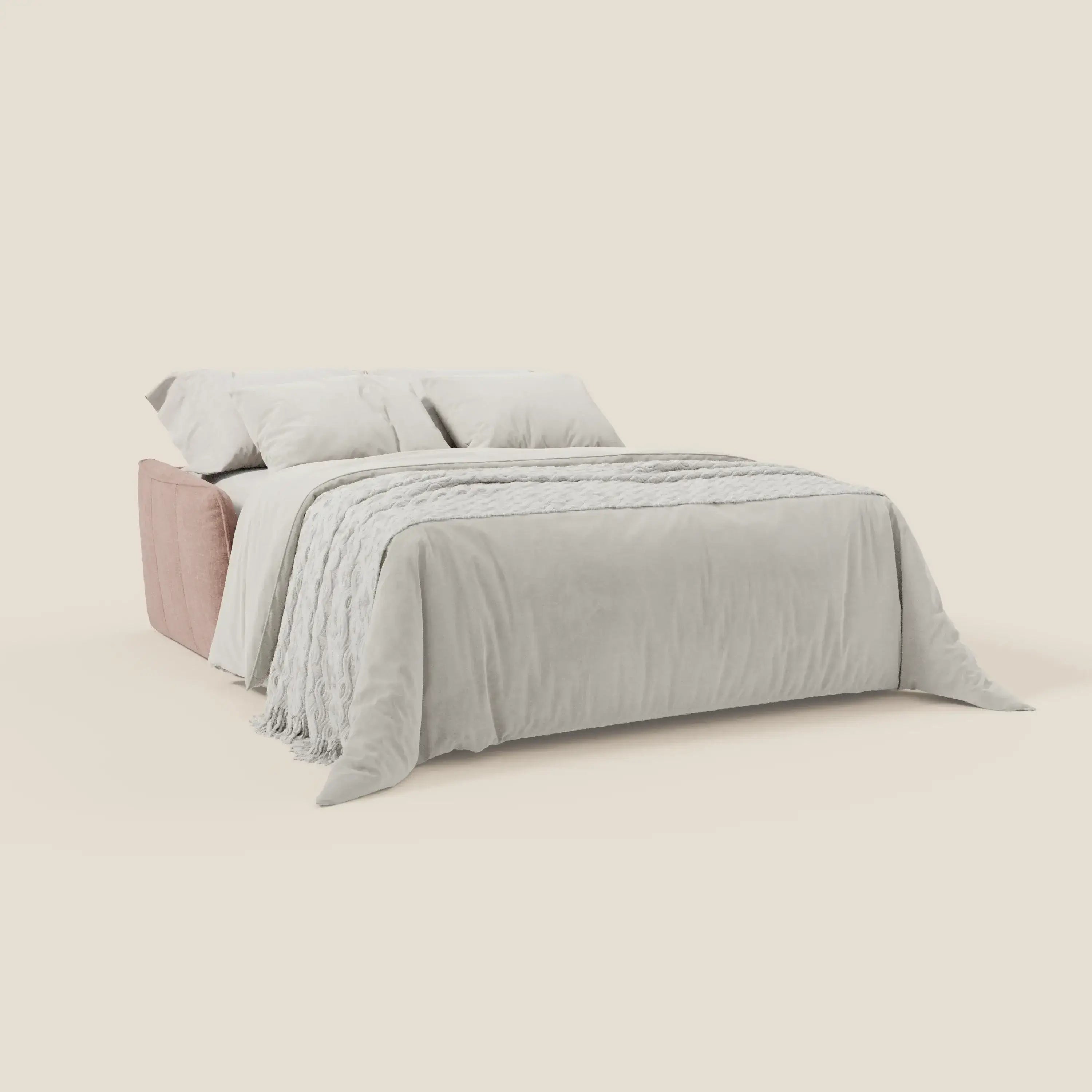 Il letto Elios Divano di Divani.Store è caratterizzato da una struttura in tessuto smacchiabile rosa chiaro T24 rosa cipria con cuscini di schienale in tessuto, cuscini bianchi, un piumone bianco e una coperta in tessuto, su uno sfondo beige.