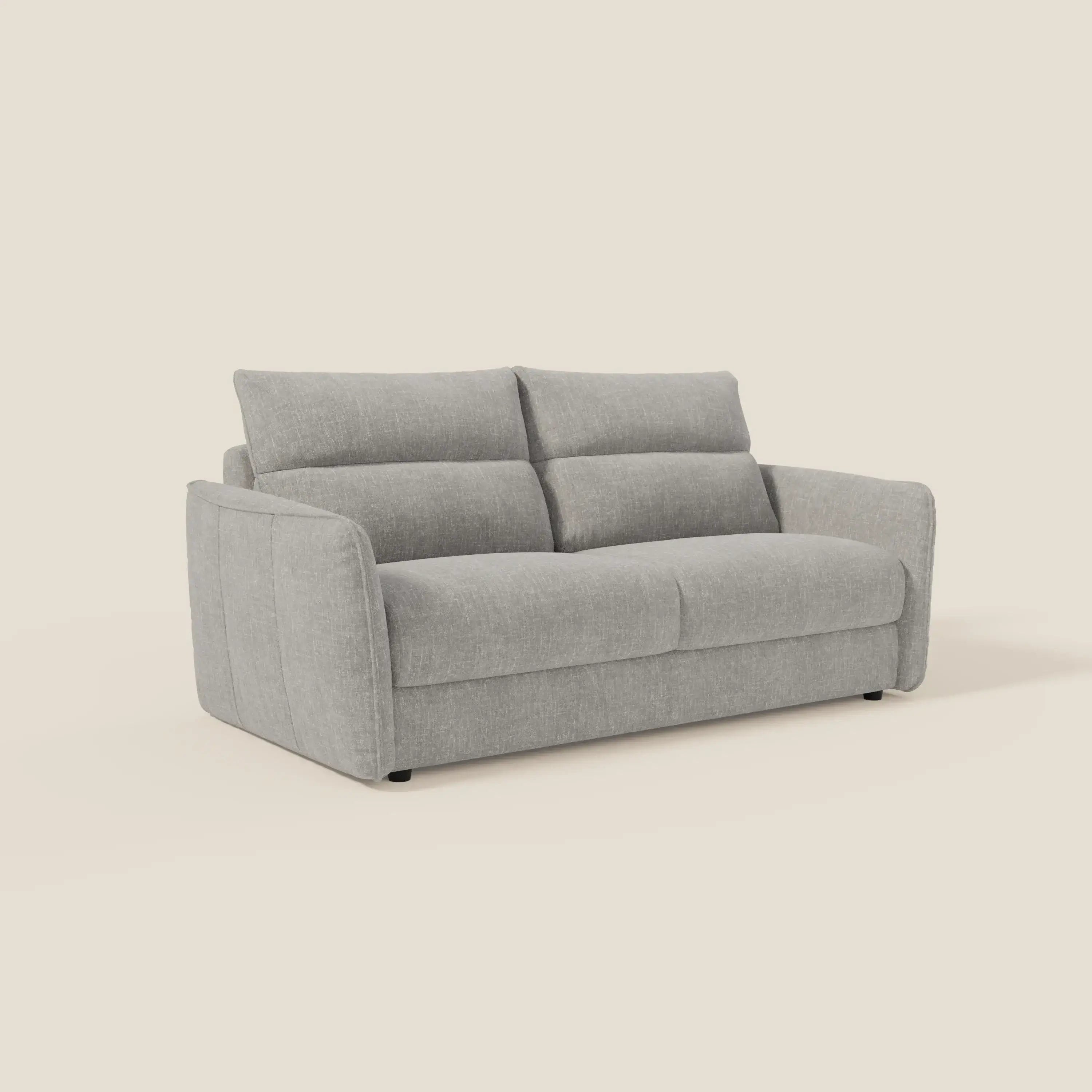 Il divano letto Elios con morbidi cuscini spalliera in tessuto smacchiabile T24 grigio di Divani.Store è caratterizzato da un design moderno in tessuto grigio chiaro, ampi braccioli, imbottitura morbida e poggia su piccoli piedini neri su uno sfondo bianco sporco.