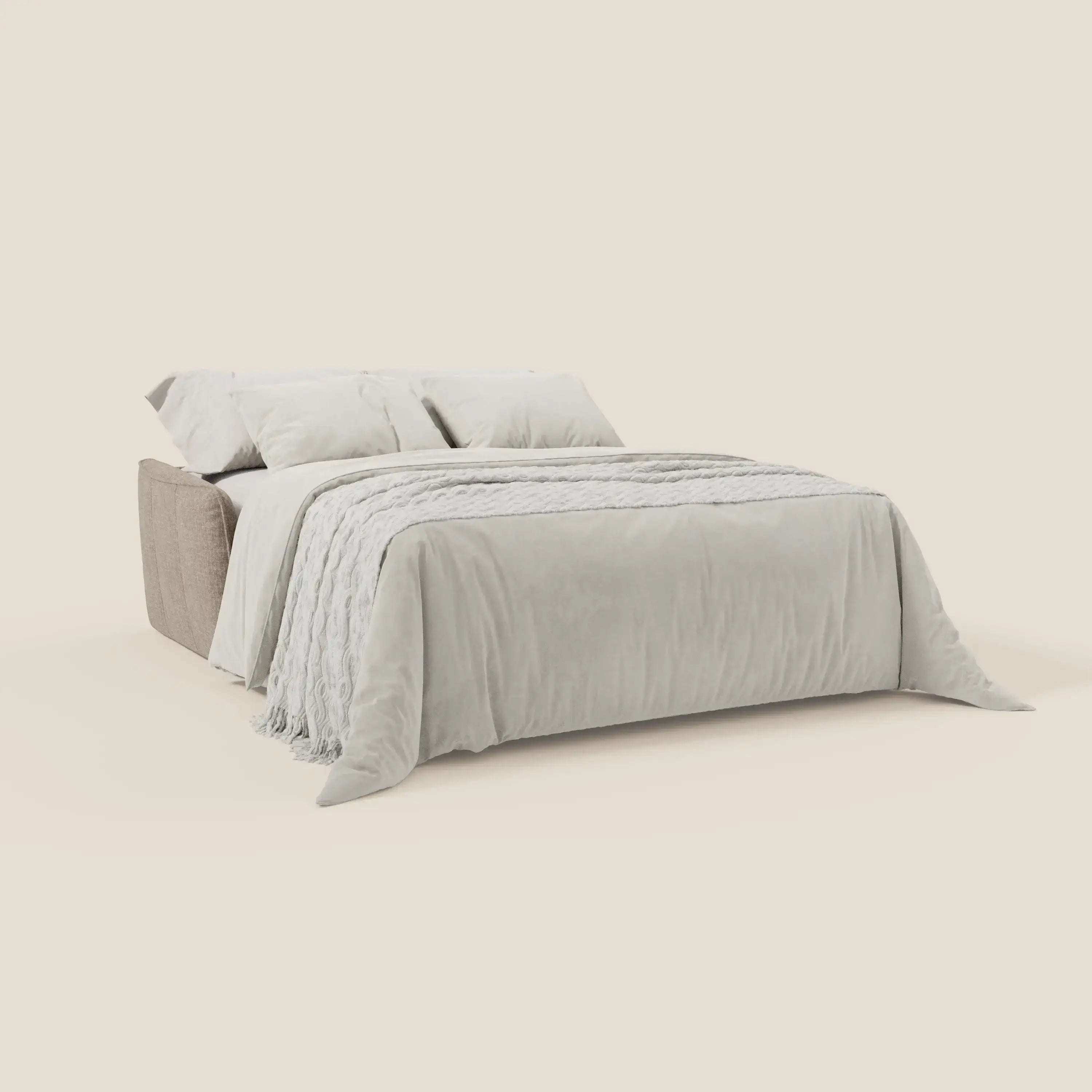 Il divano letto Elios di Divani.Store è caratterizzato da un tessuto lavabile T24 marrone tortora con morbidi cuscini di schienale, disposti in modo ordinato con biancheria da letto grigio chiaro, due cuscini e una coperta strutturata su un semplice sfondo crema.