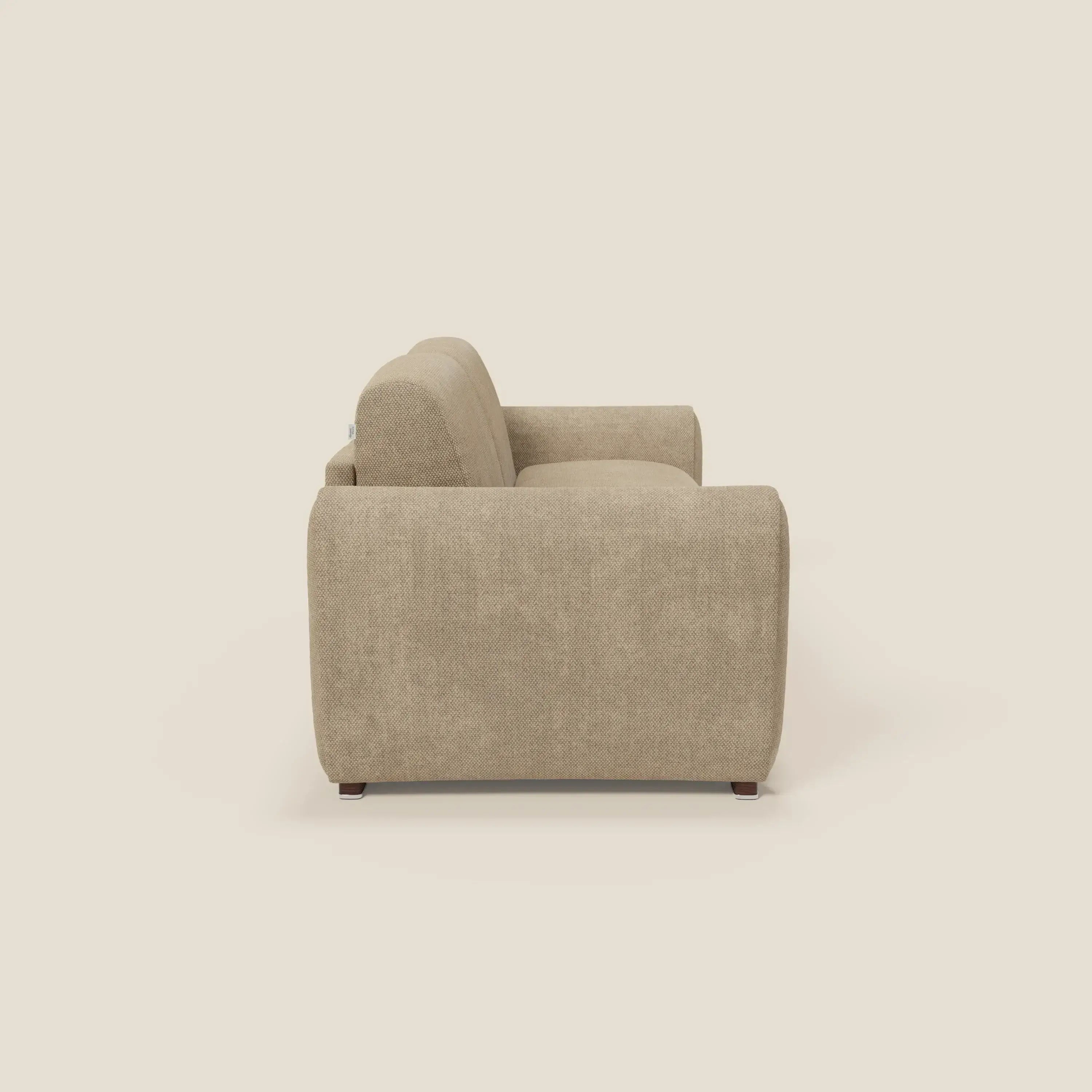 Vista laterale di Kaleo Divano letto moderno di Divani.Store in tessuto impermeabile T26 beige, caratterizzato da ampi braccioli arrotondati, schienale morbido, design minimalista e contemporaneo e piccole gambe in legno su uno sfondo crema chiaro.