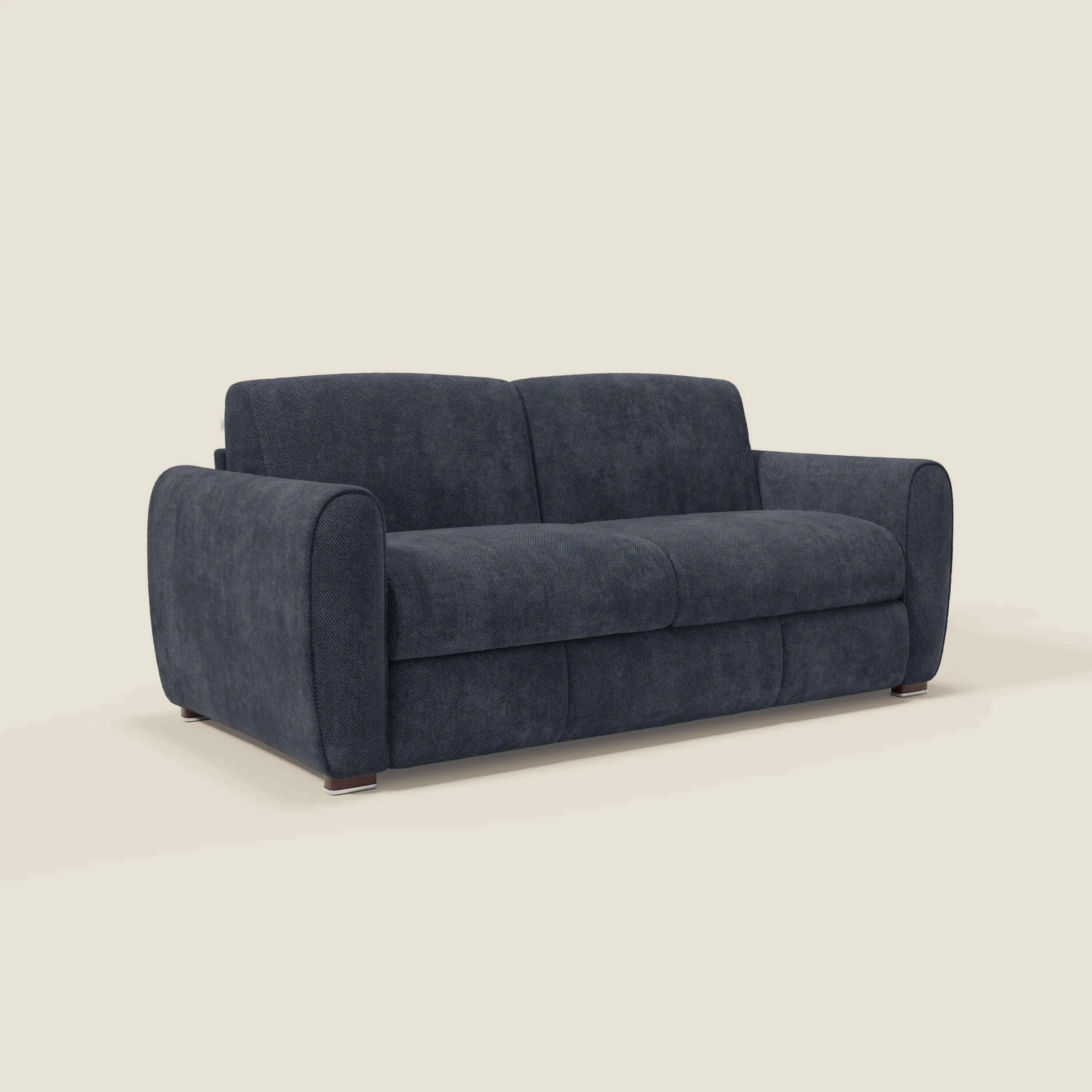 Il Kaleo Divano letto moderno di Divani.Store è caratterizzato da un tessuto impermeabile T26 blu navy, da cuscini arrotondati e morbidi, da braccioli, da uno schienale basso e da piedini corti in legno. L'immagine è su uno sfondo beige chiaro. Altezza materasso: 17 cm.