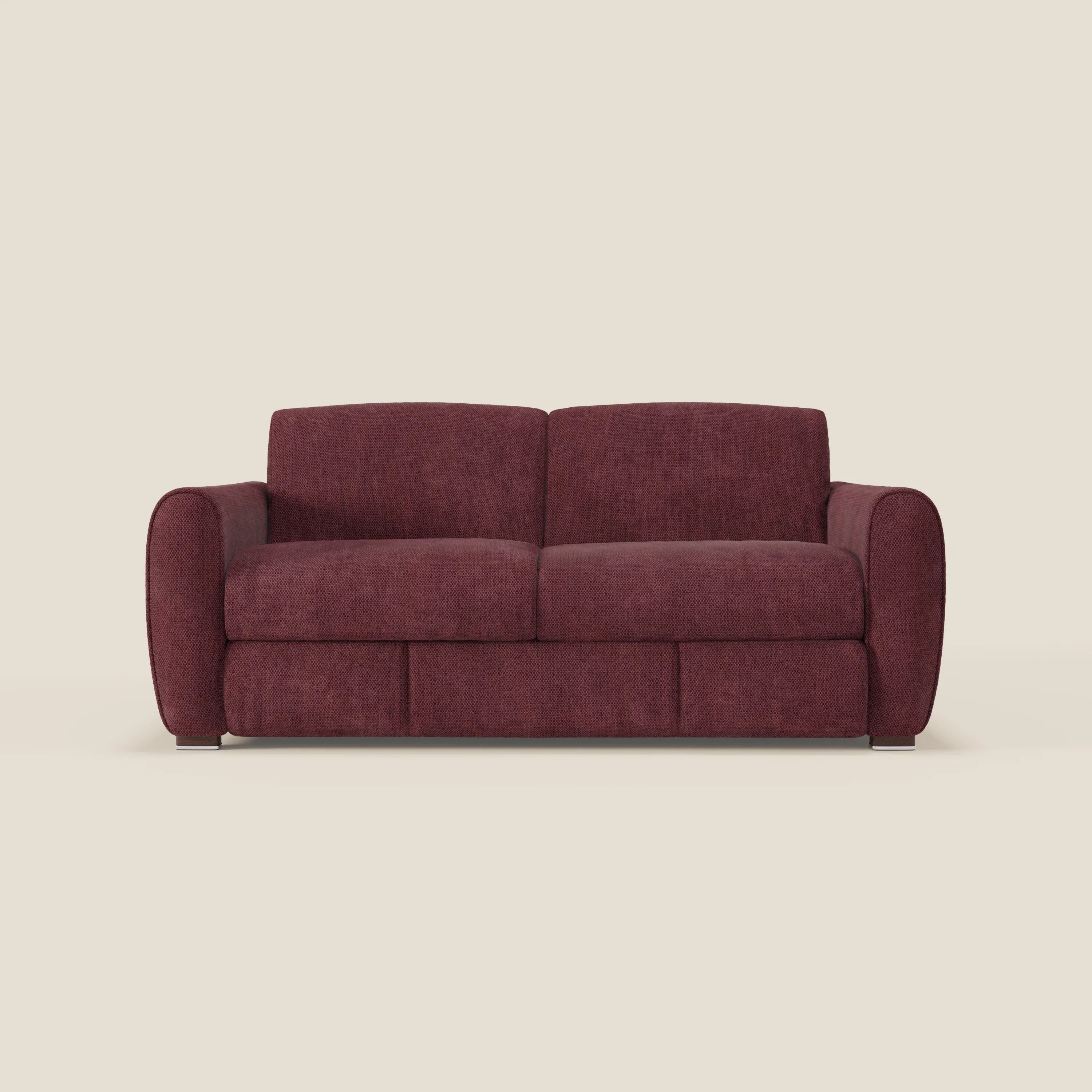 Il divano letto moderno Kaleo di Divani.Store è caratterizzato da due cuscini per la seduta e lo schienale, braccioli imbottiti arrotondati e morbido tessuto impermeabile T26 bordeaux prugna. Poggia su gambe corte e scure su uno sfondo beige chiaro.