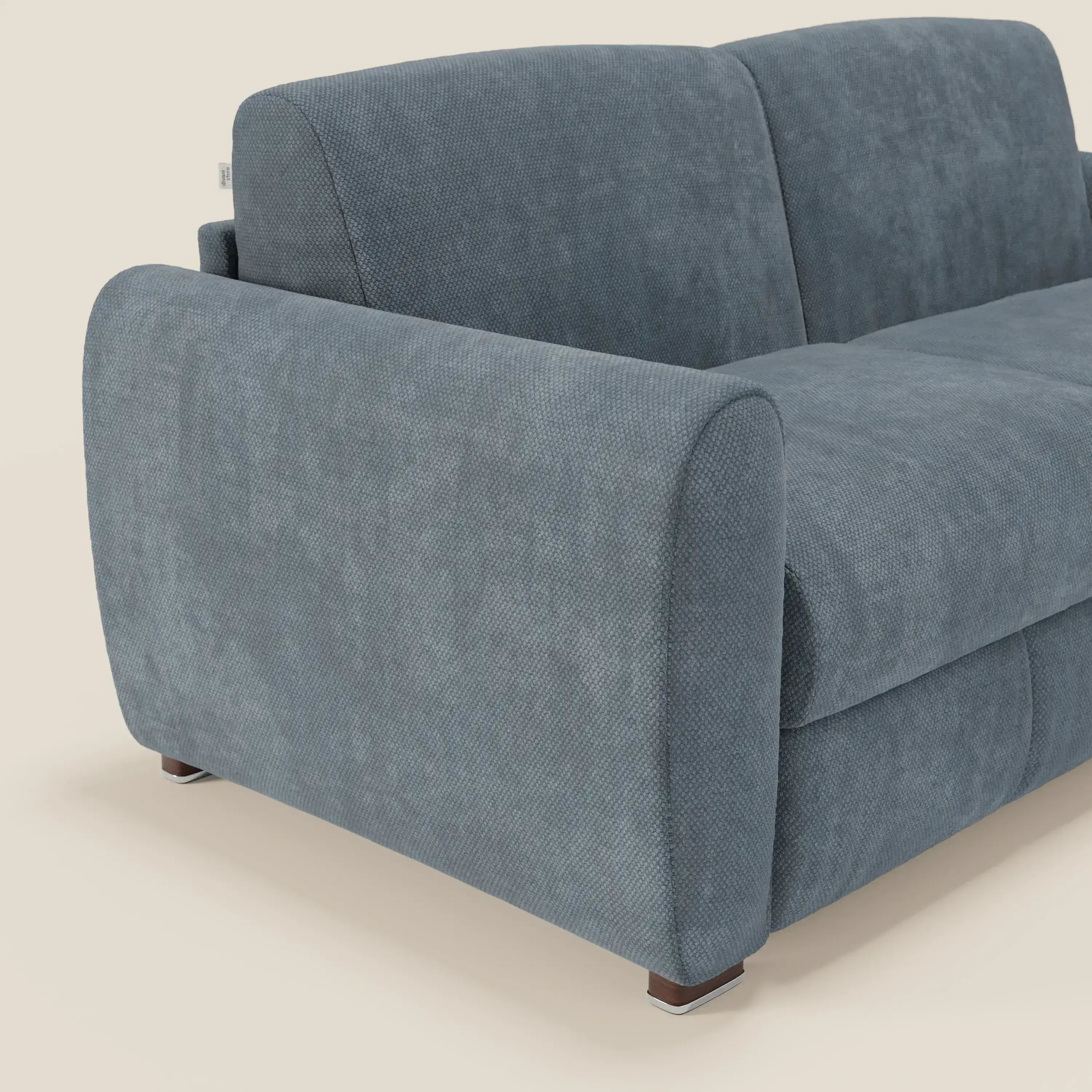 Il divano letto moderno Kaleo di Divani.Store è caratterizzato da tessuto impermeabile T26 carta da zucchero, schienale alto, braccioli arrotondati e gambe corte in legno con accenti metallici. Su uno sfondo crema chiaro; solo una parte è visibile.