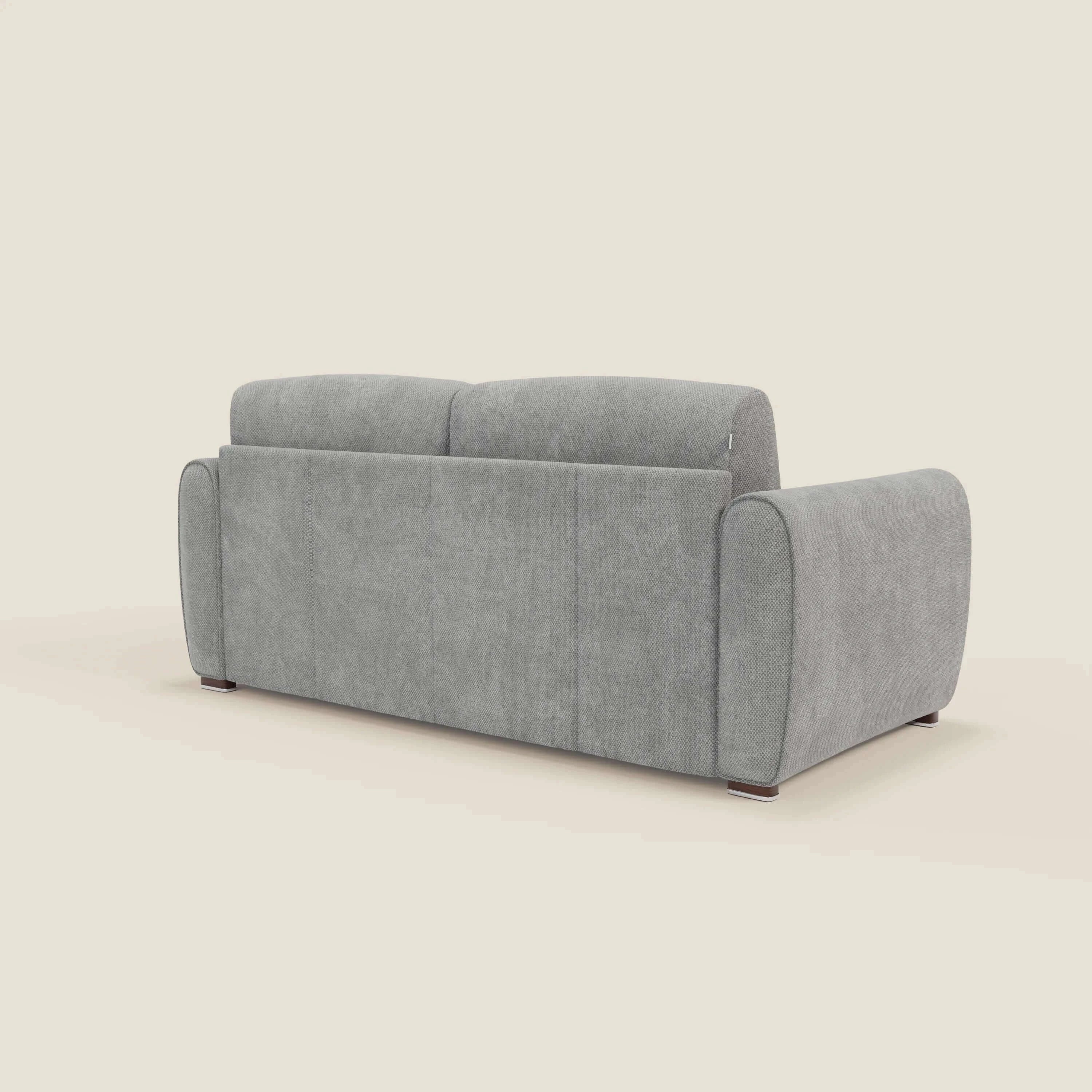 Il Kaleo Divano letto moderno con materasso H17 cm di Divani.Store, in raffinato tessuto impermeabile T26 grigio, è mostrato dietro e di lato su sfondo neutro, con ampi braccioli arrotondati e gambe corte dal design contemporaneo.