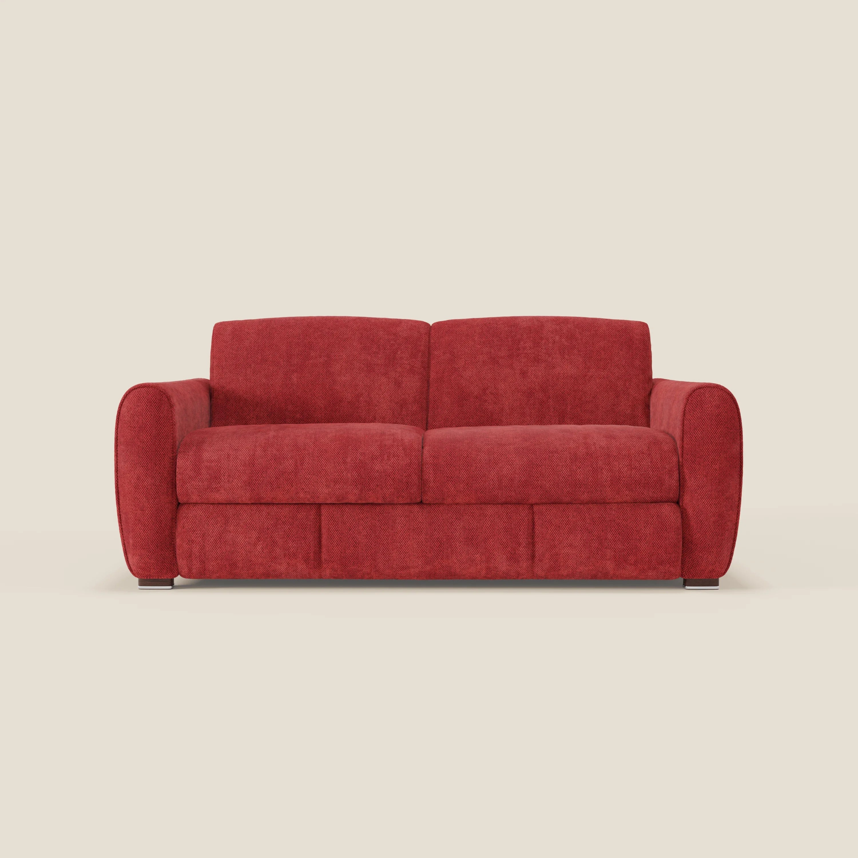 Il Kaleo Divano letto moderno di Divani.Store in tessuto impermeabile T26 rosso vivo, due posti, con cuscini imbottiti e braccioli arrotondati, poggia su piedi scuri bassi contro uno sfondo beige chiaro. Materasso H17 cm incluso.