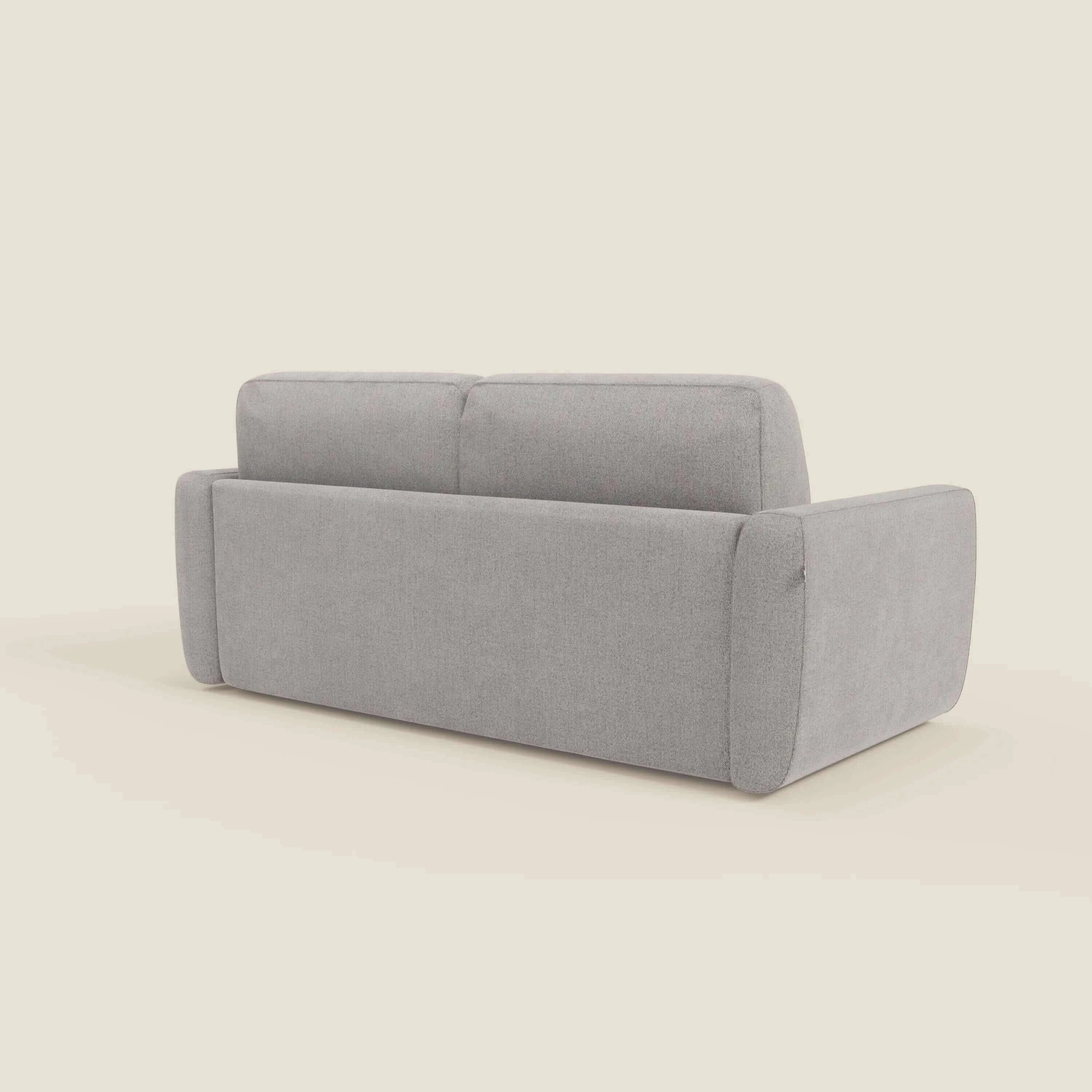 Il divano letto sfoderabile Leonida di Divani.Store è presentato in posizione angolare, con spessi braccioli imbottiti e un materasso H18 cm ad alta densità in tessuto Smacchiabile T23 grigio su uno sfondo beige chiaro.