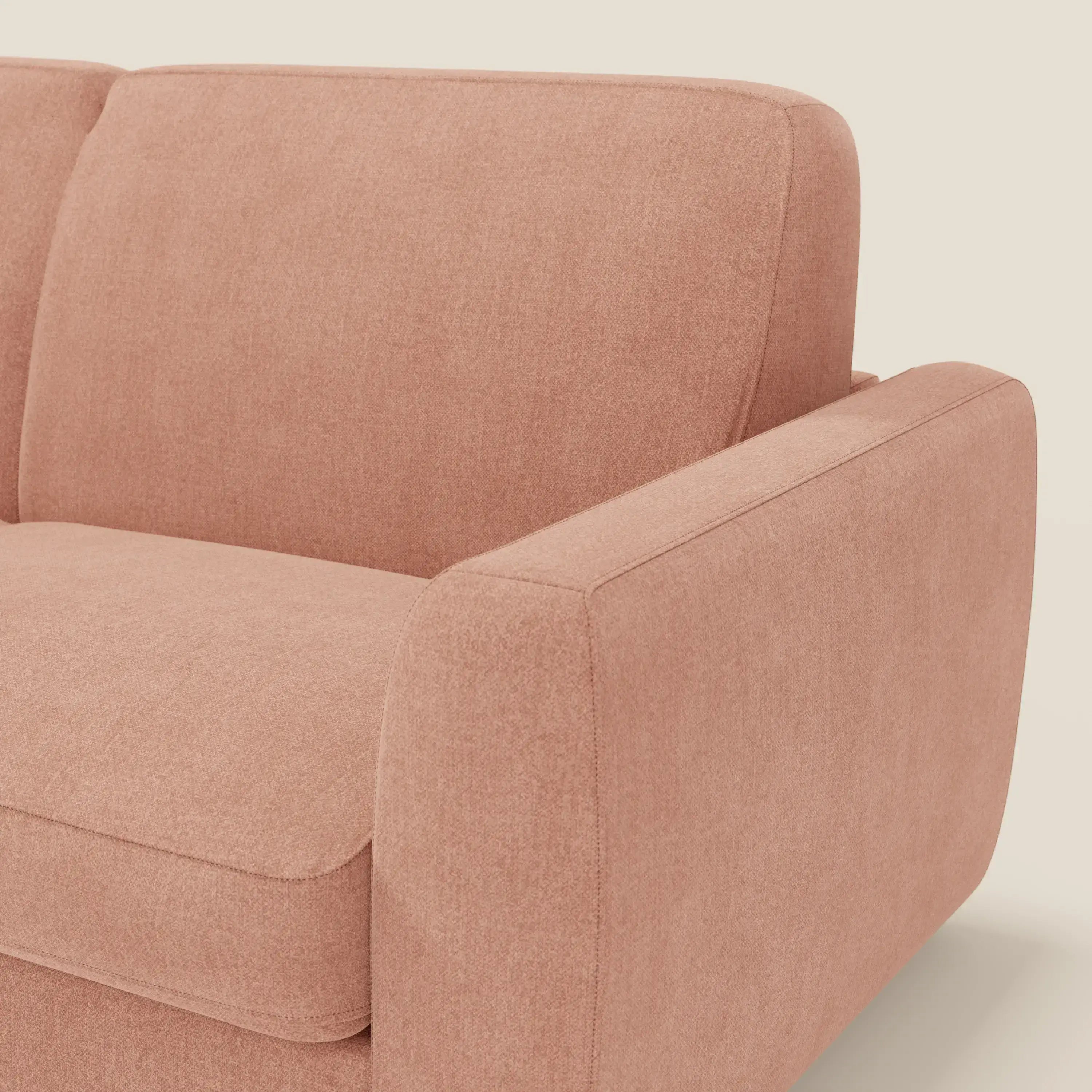 Primo piano del divano letto sfoderabile Leonida di Divani.Store in tessuto antimacchia T23 pesca, con cuscini in tessuto felpato, ampio bracciolo e materasso spesso H18 cm: un comfort perfetto con vano porta guanciali incorporato.