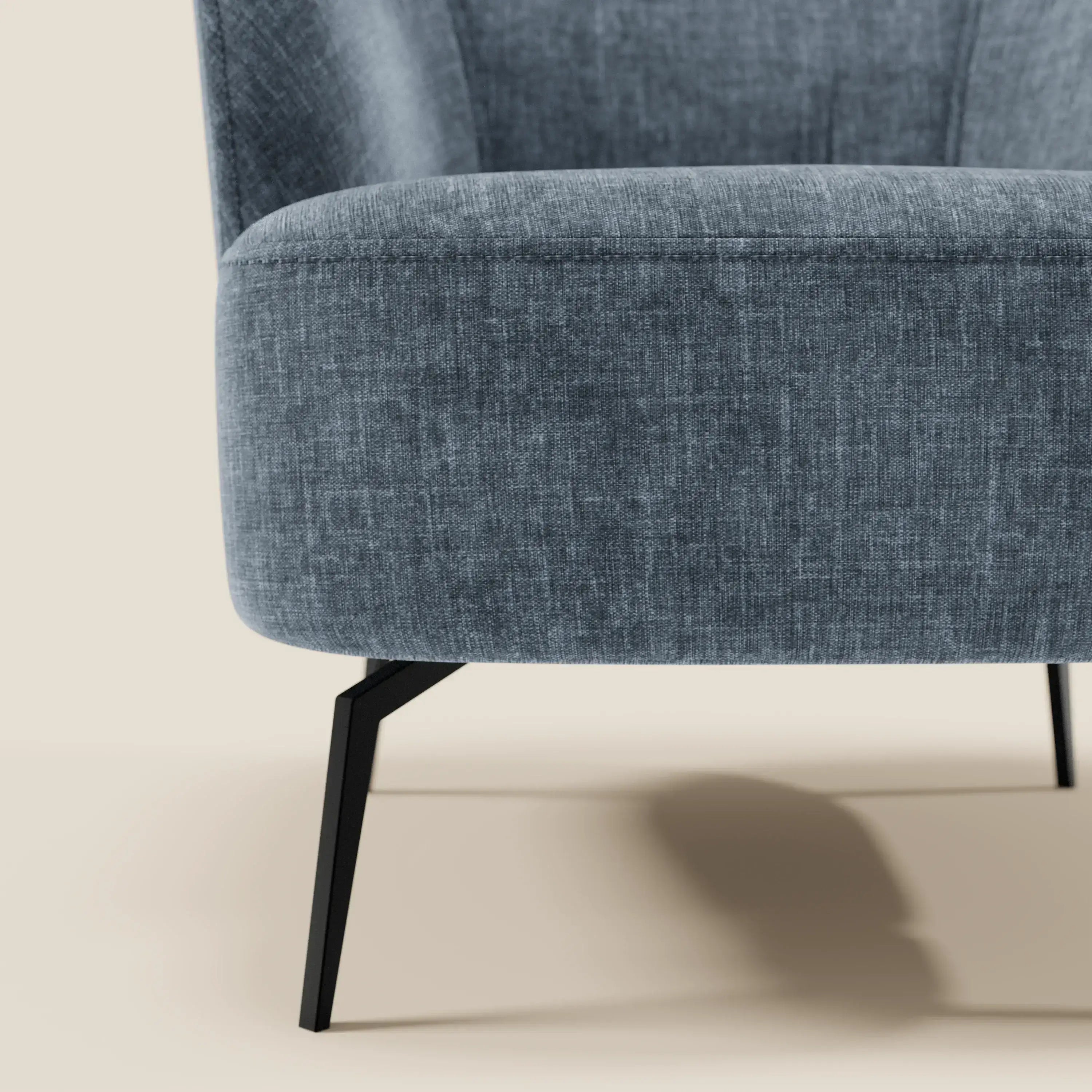 Primo piano di Renoa Poltroncina dall'eleganza moderna di Divani.Store, rivestita in tessuto smacchiabile T24 blu ardesia, con gambe in metallo angolate nere e schienale curvo che ne accentua il design elegante e minimalista.