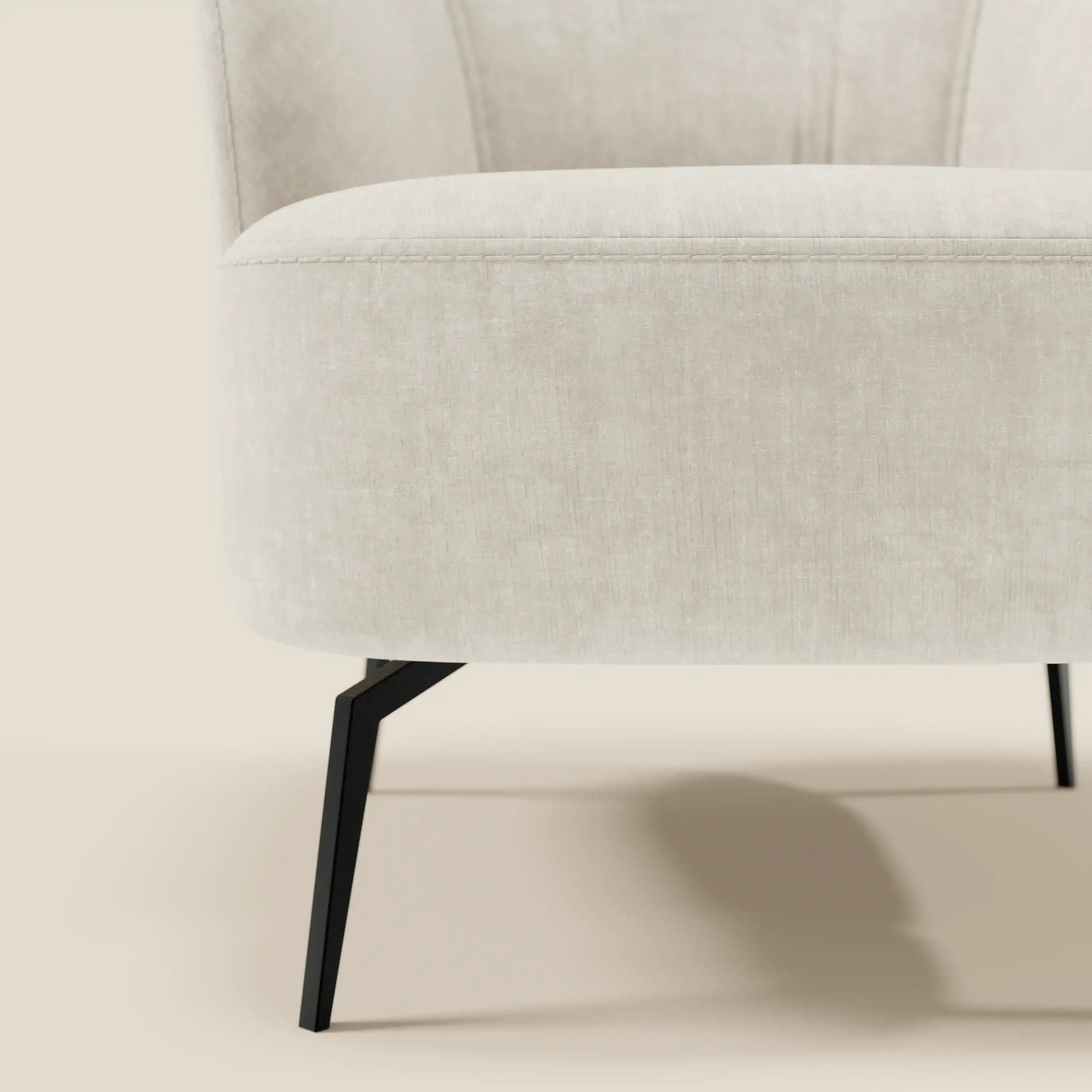 Primo piano della poltroncina Divani.Store Renoa dall'eleganza moderna, con tessuto smacchiabile T24 bianco latte e gambe sottili e angolate in metallo nero per un look minimalista ed elegante.