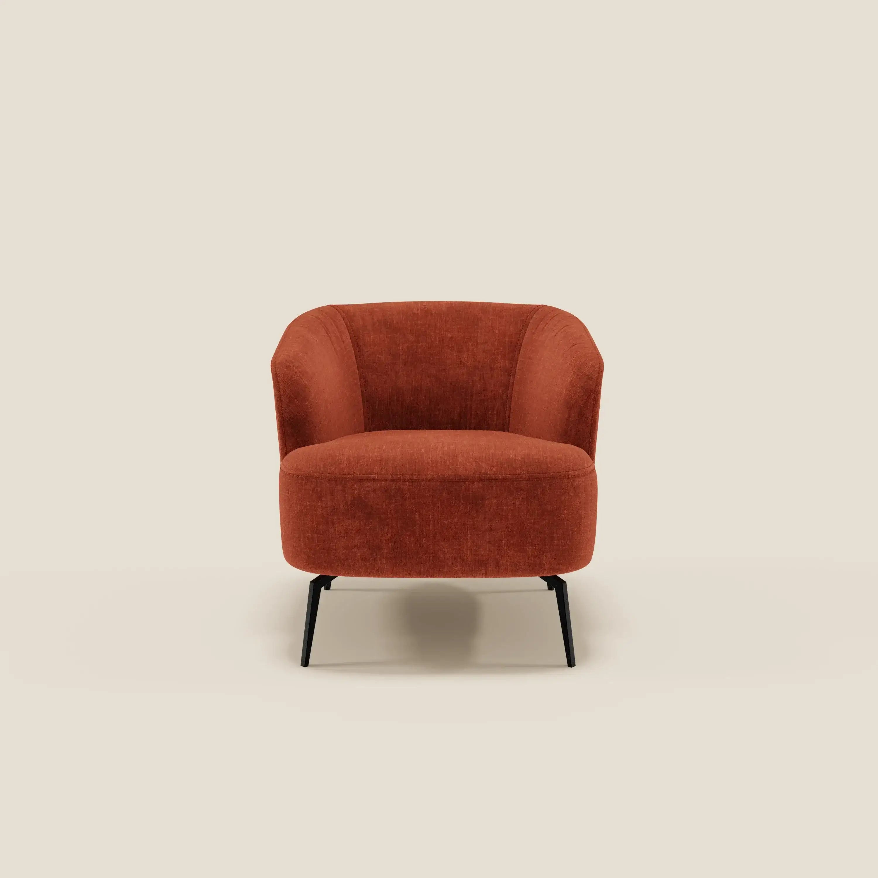 La Renoa Poltroncina di Divani.Store, dall'eleganza moderna, è rivestita in tessuto smacchiabile T24 ruggine con schienale e seduta arrotondati e sottili gambe in metallo nero. Sfondo beige chiaro minimalista.