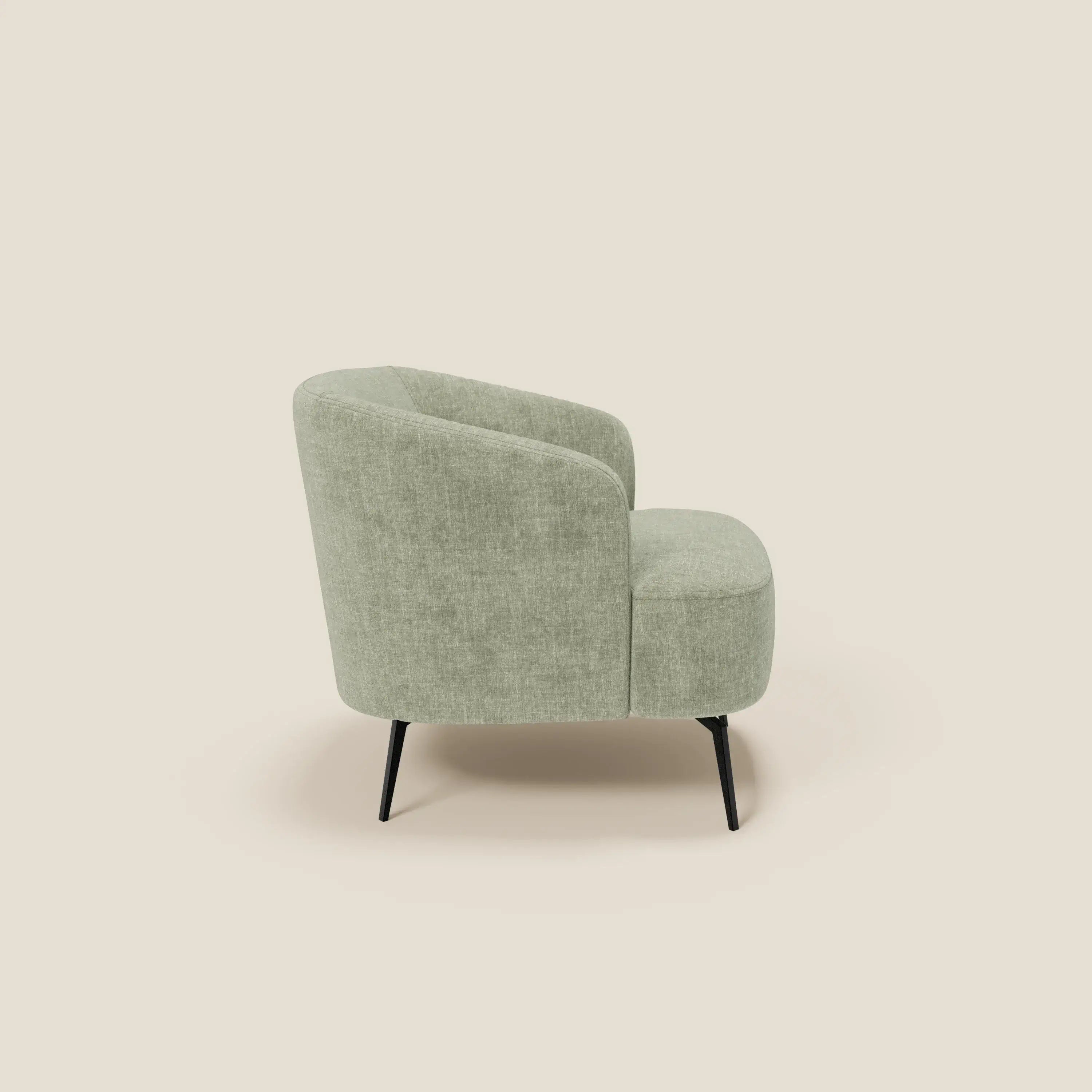 La poltroncina Renoa di Divani.Store, in tessuto smacchiabile T24 verde salvia, presenta uno schienale e una seduta curvi per un comfort avvolgente. Le sottili gambe in metallo nero esaltano il suo design moderno, presentato su un semplice sfondo beige.