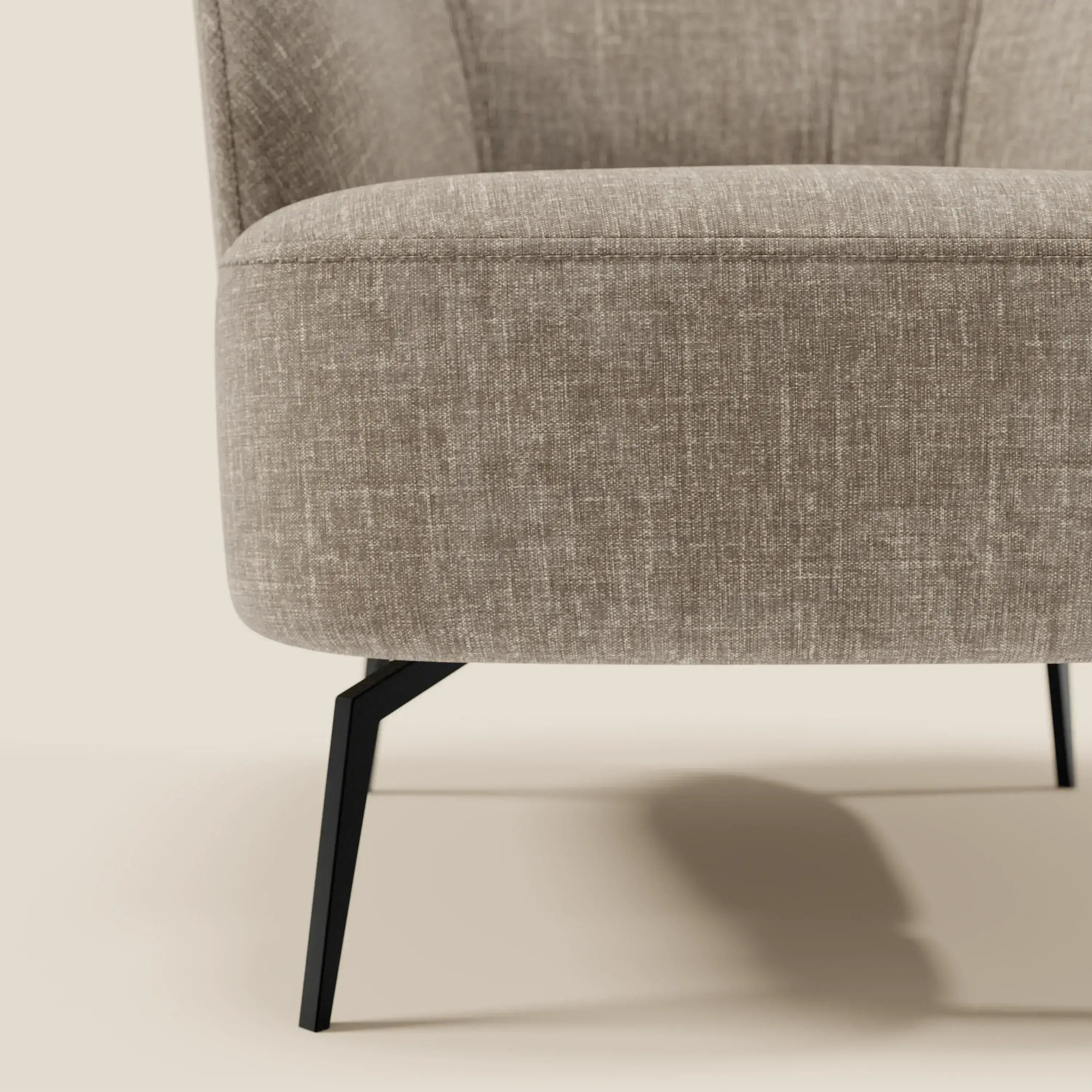 Primo piano della poltroncina Renoa dall'eleganza moderna di Divani.Store, rivestita in tessuto smacchiabile T24 marrone tortora. La seduta curva e le gambe angolate in metallo nero ne evidenziano il design moderno su uno sfondo neutro.