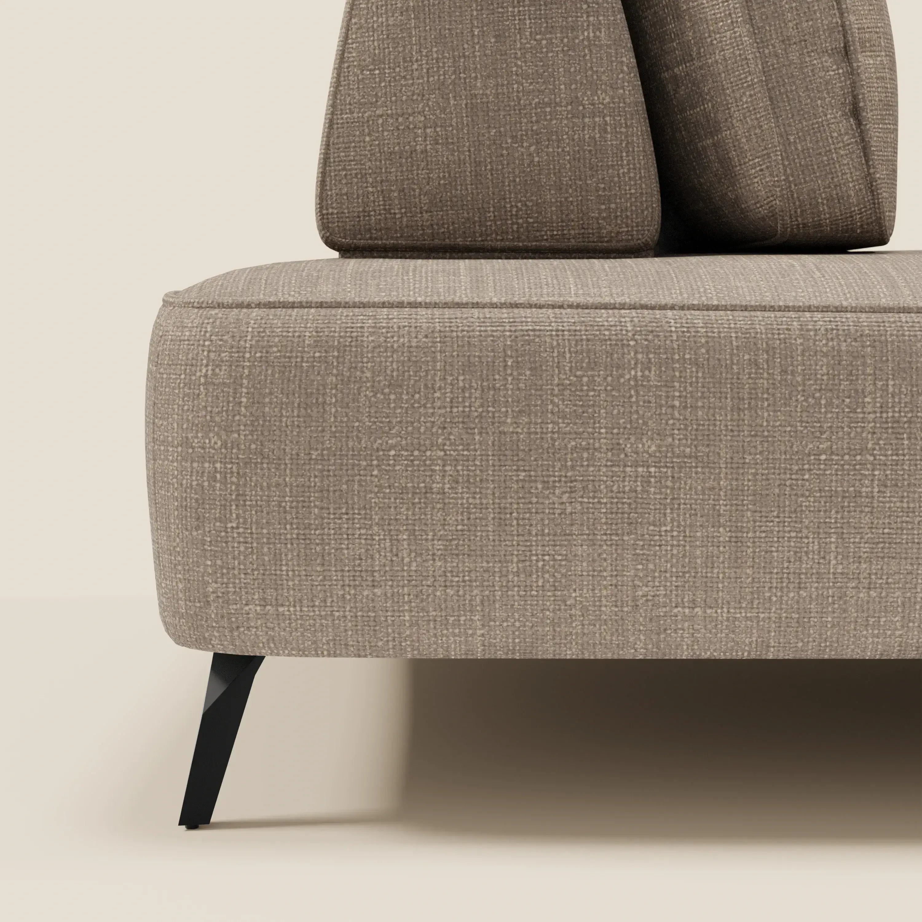Primo piano del divano modulare Volta di Divani.Store, caratterizzato da schienali mobili e seduta imbottita in raffinato tessuto ciniglia T06 tortora, con un'elegante gamba in metallo nero su uno sfondo beige neutro.