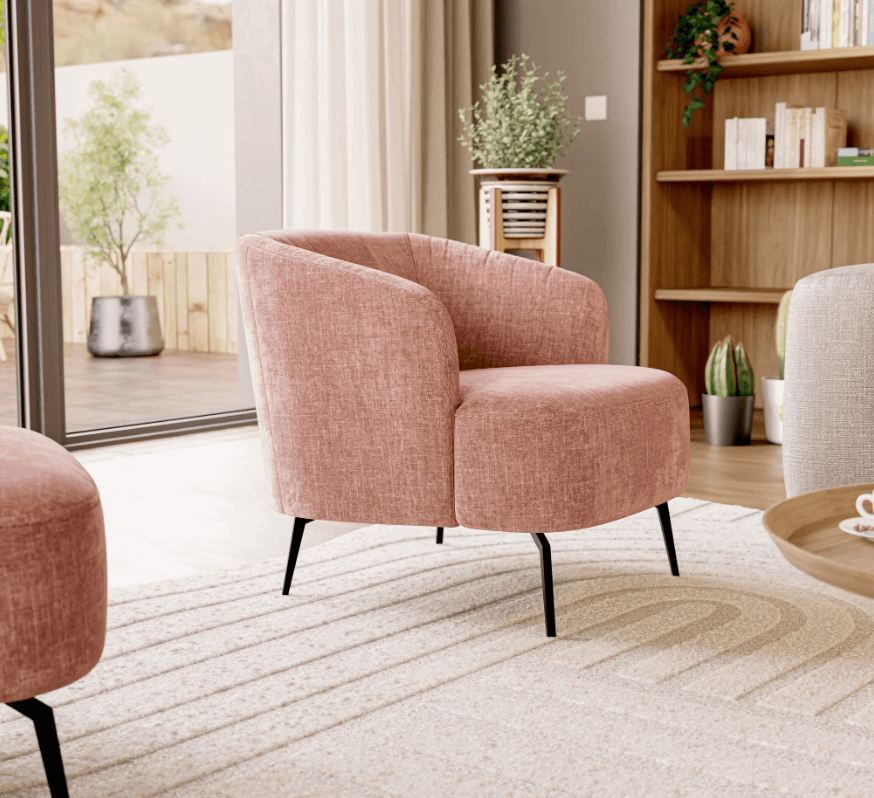 Un soggiorno moderno presenta la poltroncina Renoa dall'eleganza moderna in tessuto smacchiabile T24 rosa cipria di Divani.Store, con gambe nere su un tappeto beige, circondata da piante, librerie e un tavolino in legno accanto al verde del patio.