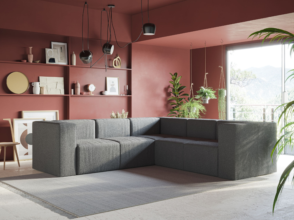 Un soggiorno moderno con un divano grigio a L, pareti rosse, scaffali aperti con decorazioni, luci nere appese, piante in vaso, un tappeto chiaro e luce del sole che filtra da una grande finestra.