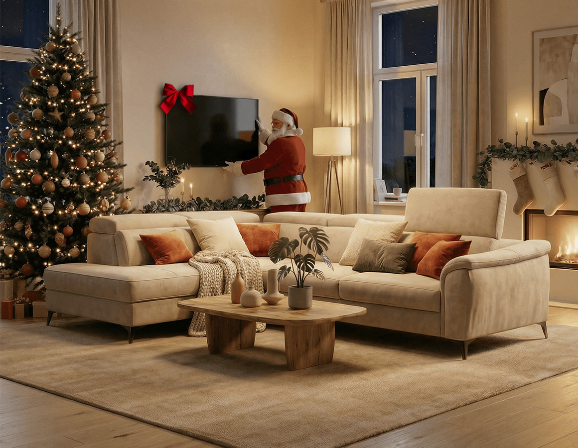 Un accogliente salotto con un albero di Natale decorato, un divano beige e un tavolino da caffè; Babbo Natale si trova vicino a un televisore a muro e un caminetto con calze e candele brilla al suo interno.