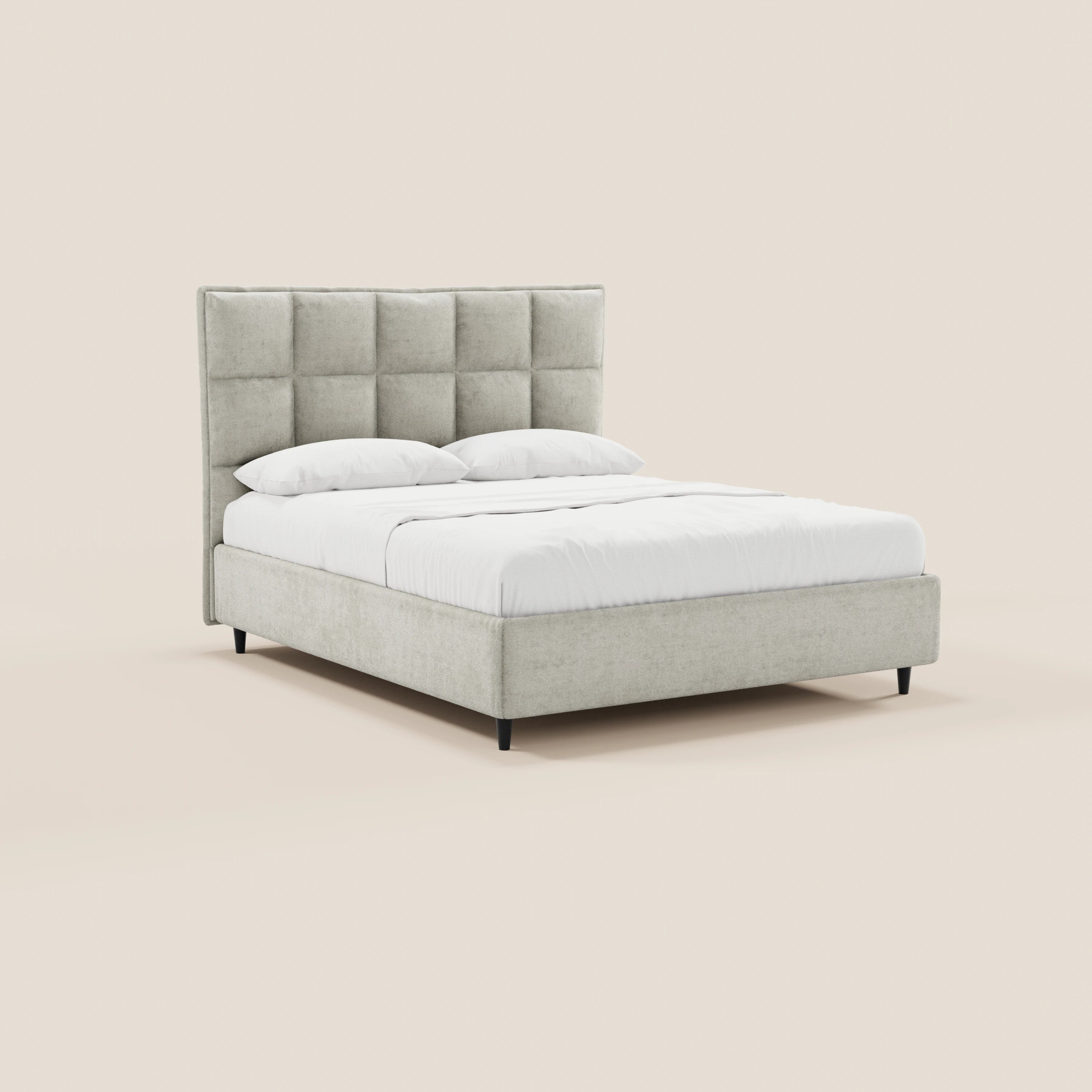 Il letto imbottito AURO con contenitore di Letti.store presenta una testiera alta e capitonné di colore grigio chiaro in ciniglia Oeko-Tex®, biancheria da letto bianca, due cuscini, una struttura a profilo ribassato con gambe nere ed è disposto su uno sfondo beige.