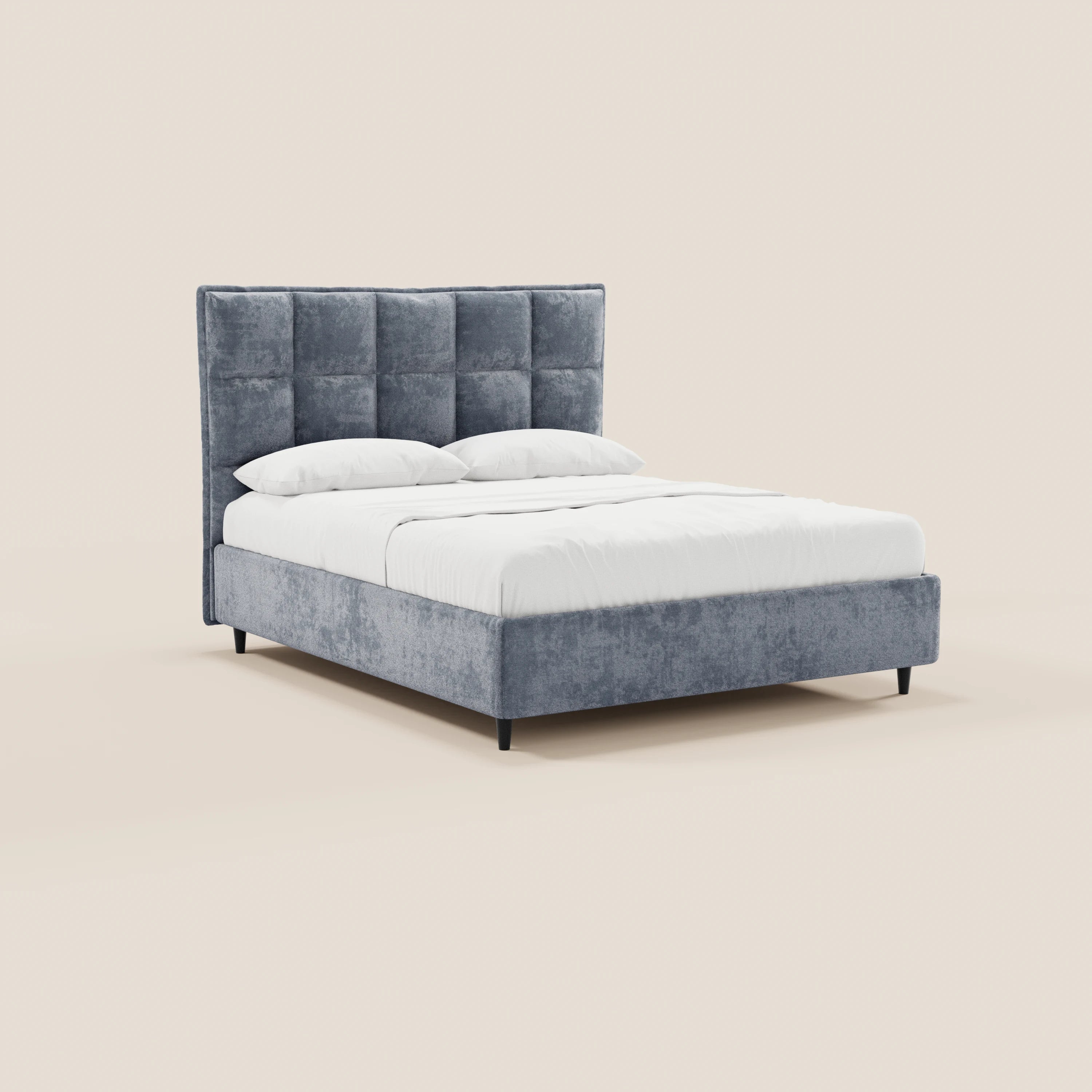 Il letto imbottito AURO con contenitore di Letti.store presenta una testiera alta grigia con rivestimento capitonné in ciniglia Oeko-Tex®, lenzuola bianche e due cuscini, ripreso su uno sfondo beige da una leggera angolazione verso destra.