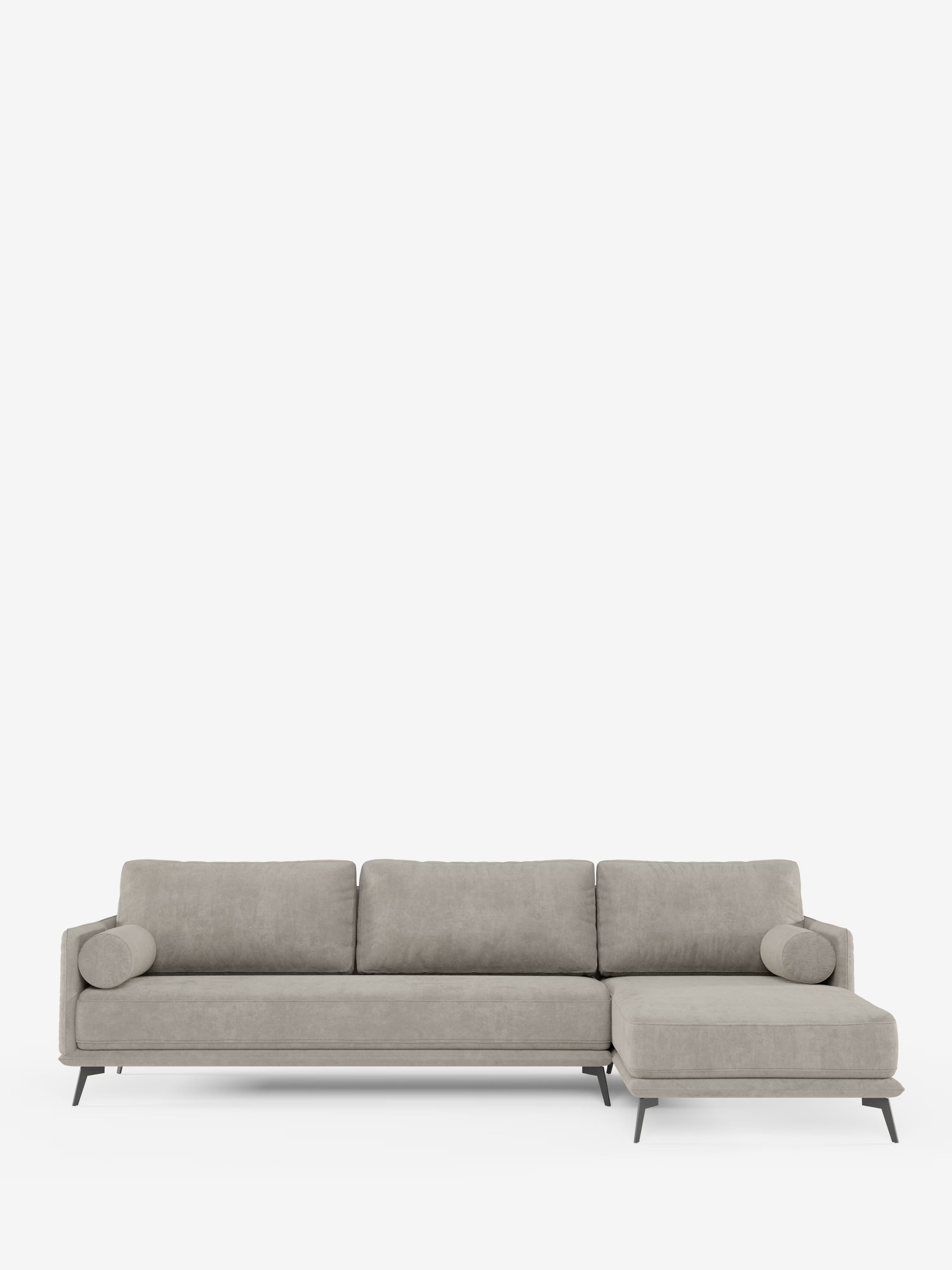 Il divano moderno angolare con penisola Basalto di Divani.Store è un divano componibile contemporaneo di colore grigio chiaro con chaise longue a destra, dotato di tre cuscini di seduta, tre cuscini di schienale, due cuscini cilindrici e sottili gambe in metallo nero. Tutti i cuscini sono imbottiti in piuma e rivestiti in tessuto T31 antimacchia, raffigurati su uno sfondo bianco a tinta unita.