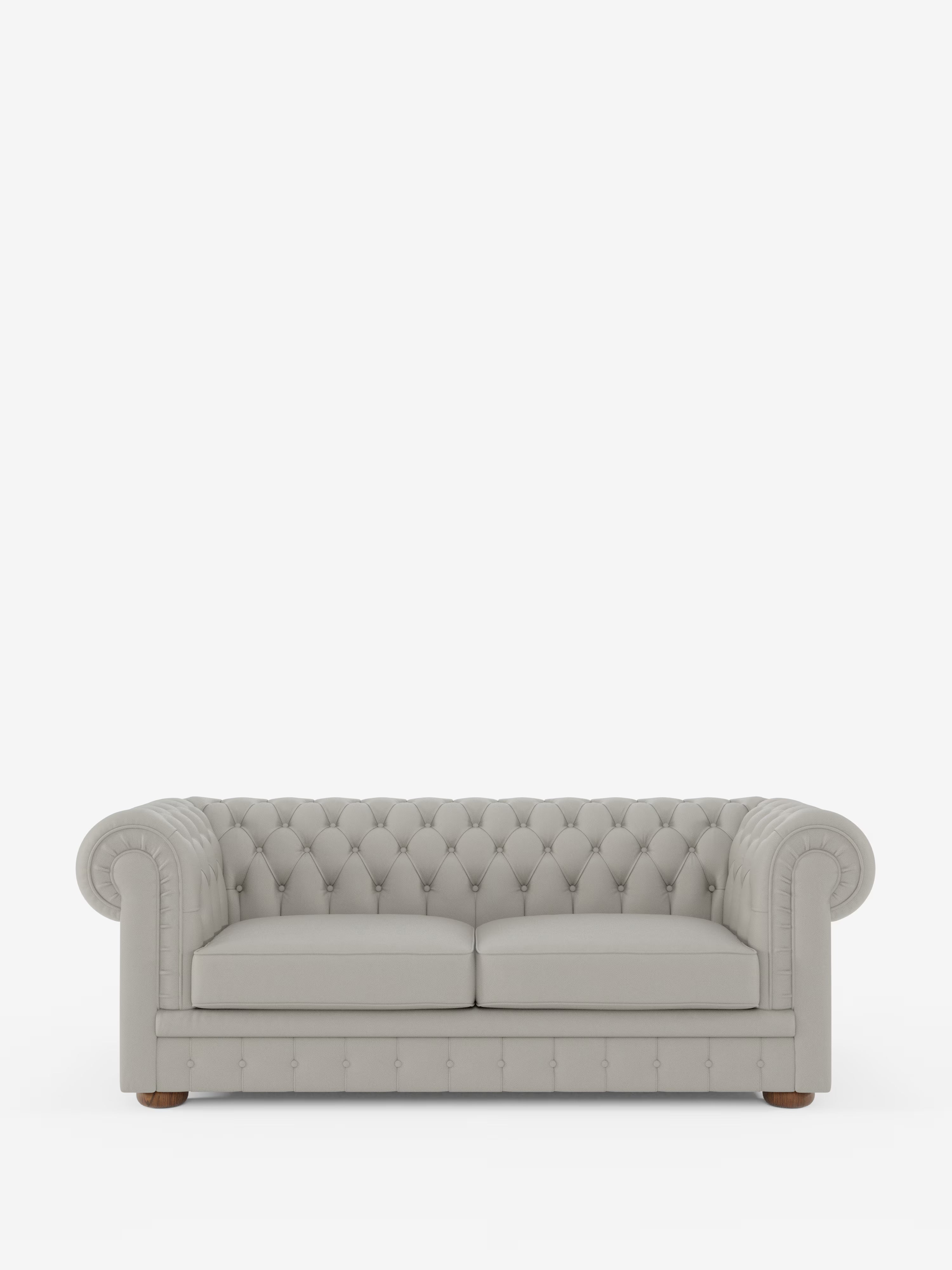 Un Chesterfield grigio chiaro – Divano Chesterfield in vera pelle spessorata a 2 e 3 posti di Divani.Store, caratterizzato da un design trapuntato con braccioli arrotondati, due cuscini di seduta e bottoni a vista sullo schienale e sui braccioli. Questo elegante divano artigianale italiano poggia su piccoli piedini in legno ed è raffigurato su uno sfondo bianco a tinta unita.