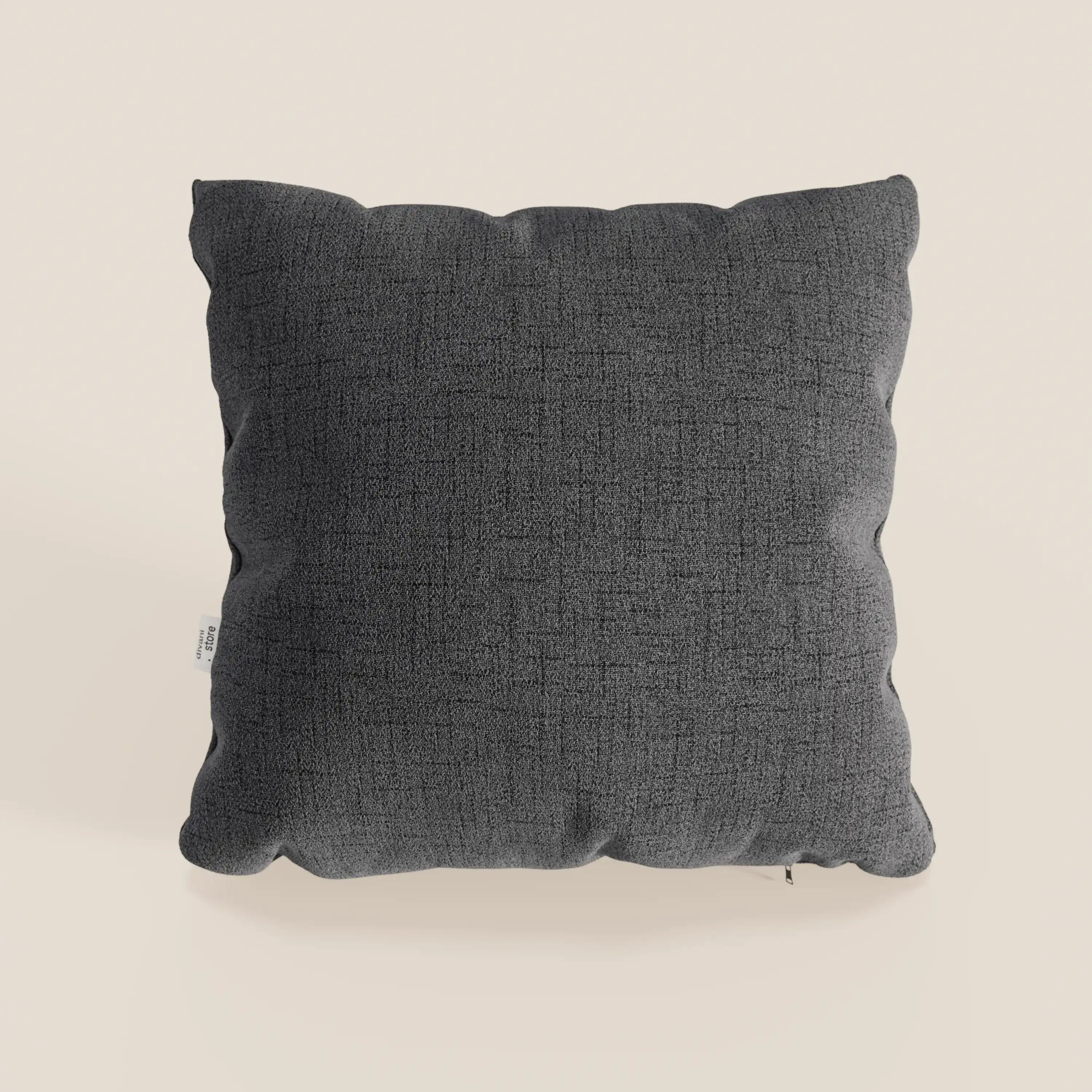 Il cuscino Felis in tessuto morbido impermeabile T03 antracite di Divani.Store, con una texture sottile e angoli arrotondati, è presentato su uno sfondo beige chiaro. Una piccola etichetta bianca sottolinea il look moderno del cuscino grigio scuro.
