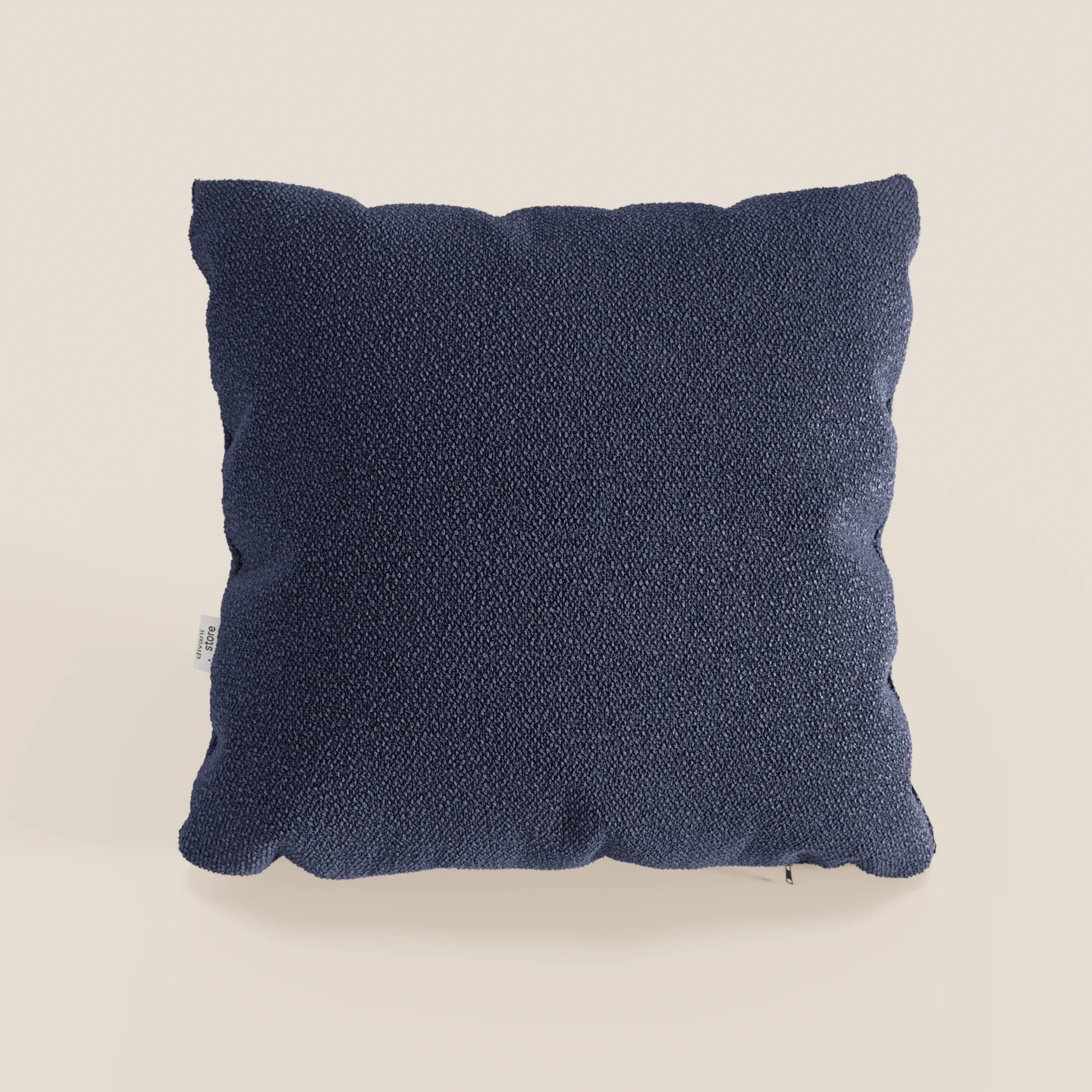 Il cuscino Lambada di Divani.Store è presentato in blu navy, con un tessuto T33 in fresco cotone naturale, lavabile e impermeabile; una piccola etichetta bianca appare sul lato su uno sfondo beige chiaro.