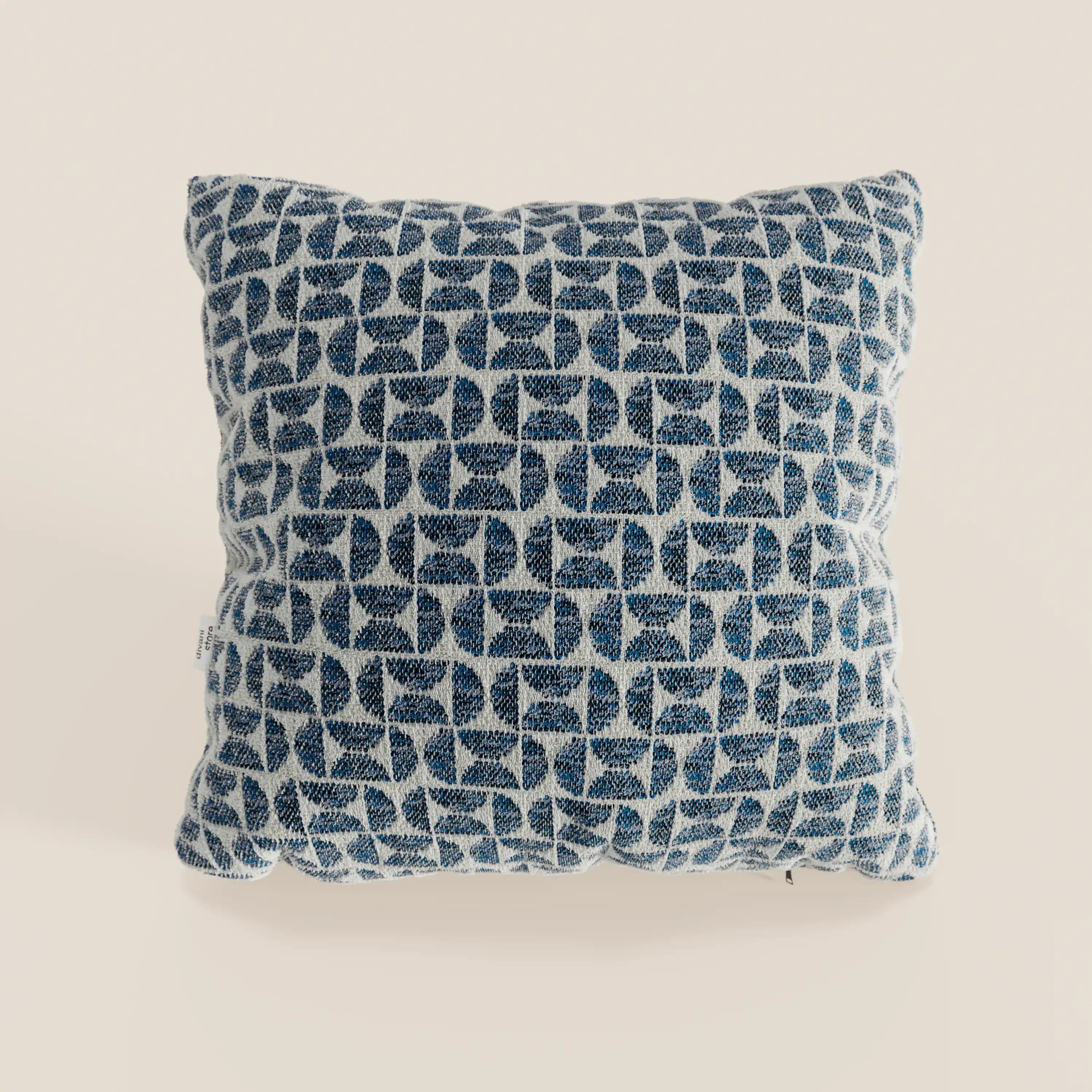 Cuscino Naxos Decoro 45x45 in lino di Divani.Store: elegante cuscino quadrato con tessuto intrecciato blu e bianco, motivo geometrico a foglie astratte su fondo crema, perfetto per decorare qualsiasi ambiente.