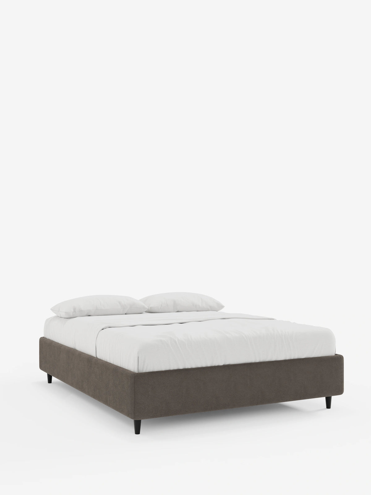 Un letto sommier imbottito ERON con contenitore, rivestito in tessuto impermeabile certificato Oeko-Tex color marrone scuro, poggia su corte gambe nere ed è adornato da lenzuola bianchissime e due morbidi cuscini su uno sfondo bianco sporco.