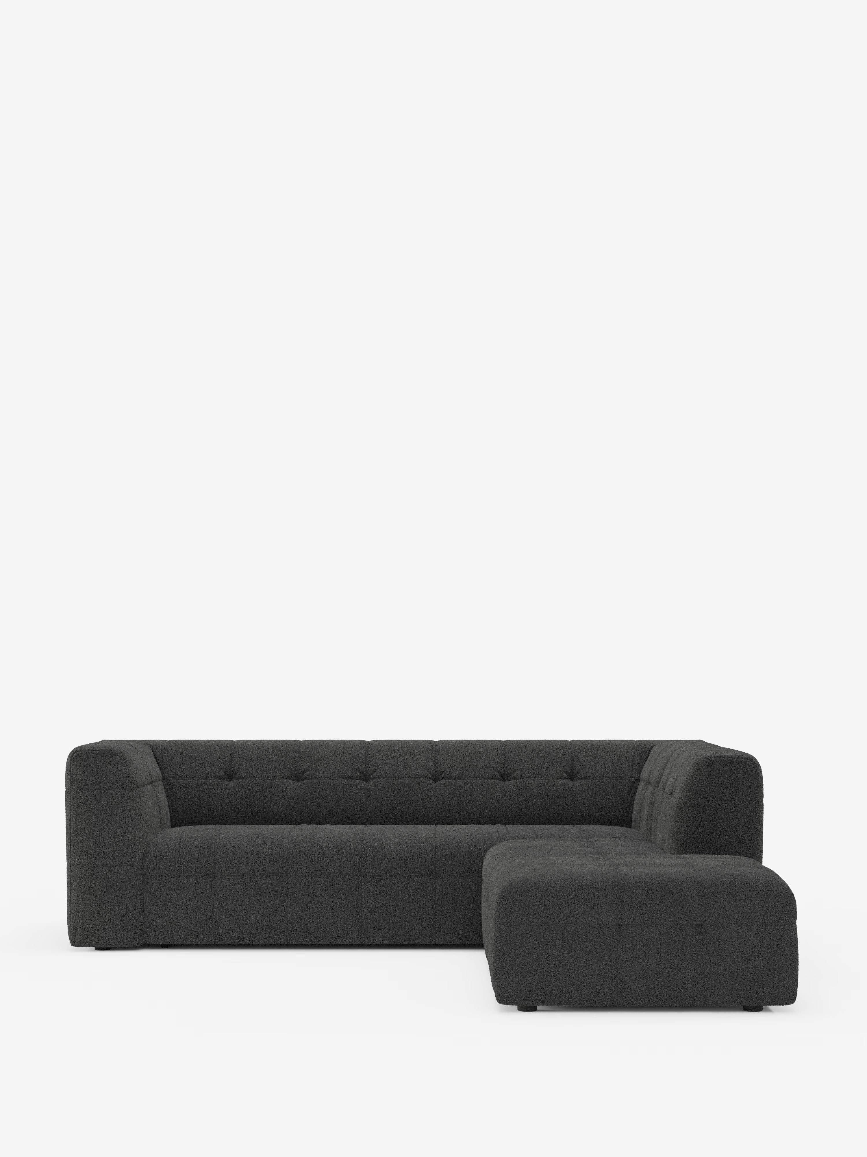 Un divano angolare componibile e modulare Mosaic dal design moderno e dal profilo basso, realizzato in bouclé da Divani.Store e presentato in grigio scuro, presenta un rivestimento capitonné in sofisticato tessuto T21 resistente alle macchie. Il divano componibile presenta ampi braccioli e una seduta profonda, con un design minimalista e geometrico, linee pulite e gambe non visibili, il tutto su uno sfondo bianco a tinta unita.