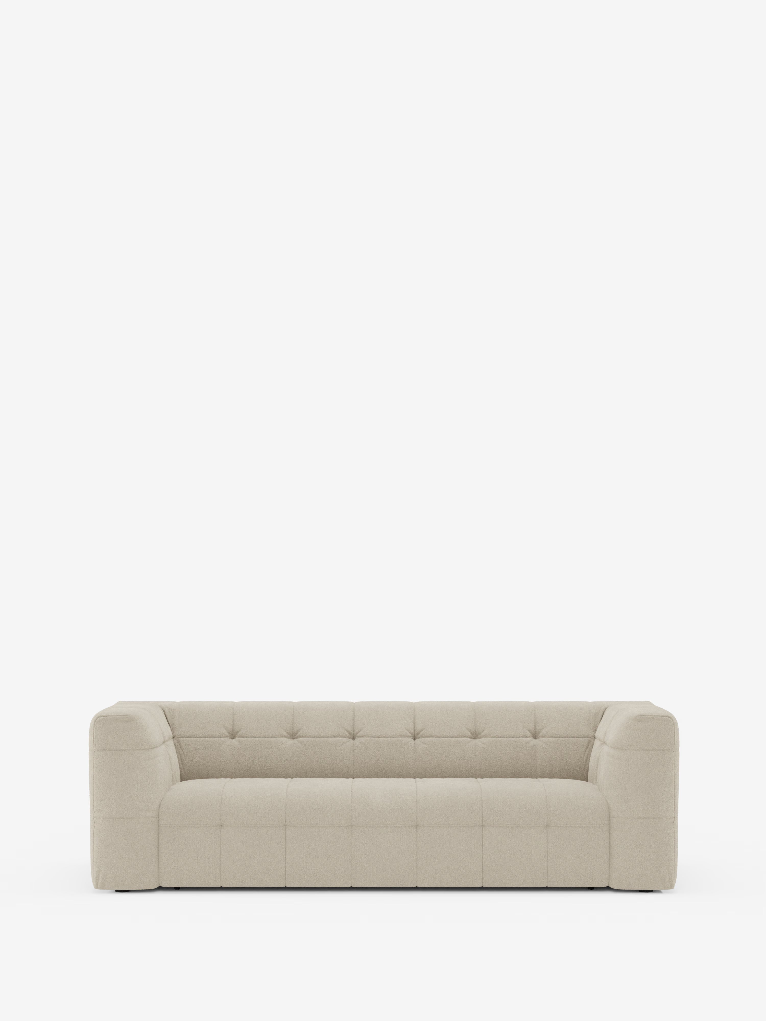 Vi presentiamo il Mosaic Divano 3 e 4 posti modulare in bouclé di Divani.Store: un moderno divano modulare in beige chiaro con schienale basso e braccioli, caratterizzato da cuciture capitonné su seduta, schienale e fianchi. Le sue linee geometriche squadrate e il tessuto T21 antimacchia risaltano sullo sfondo bianco a tinta unita, sottolineandone il design pulito e minimalista.
