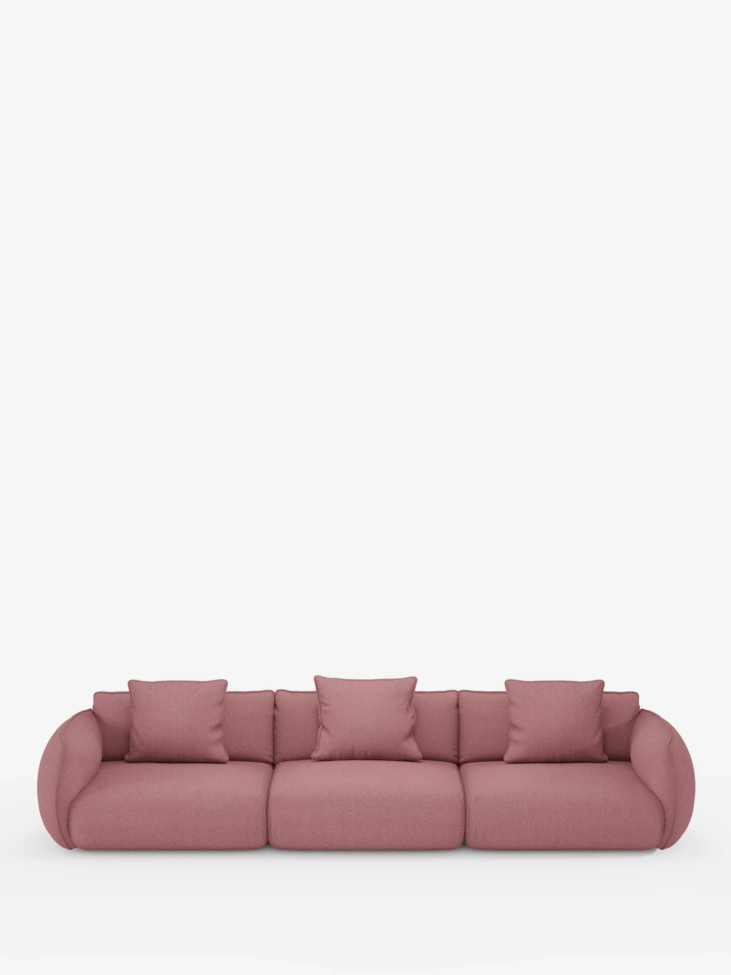 Un divano modulare contemporaneo Nimbus a 3 posti, componibile, realizzato in morbido tessuto smacchiabile effetto cotone T33 di Divani.Store, rivestito in un delicato tessuto rosa tenue, caratterizzato da braccioli e schienali leggermente arrotondati. Posizionato su uno sfondo bianco a tinta unita, questo divano elegante e facilmente smontabile comprende tre cuscini di seduta e cinque cuscini decorativi abbinati, disposti ordinatamente sulla superficie.
