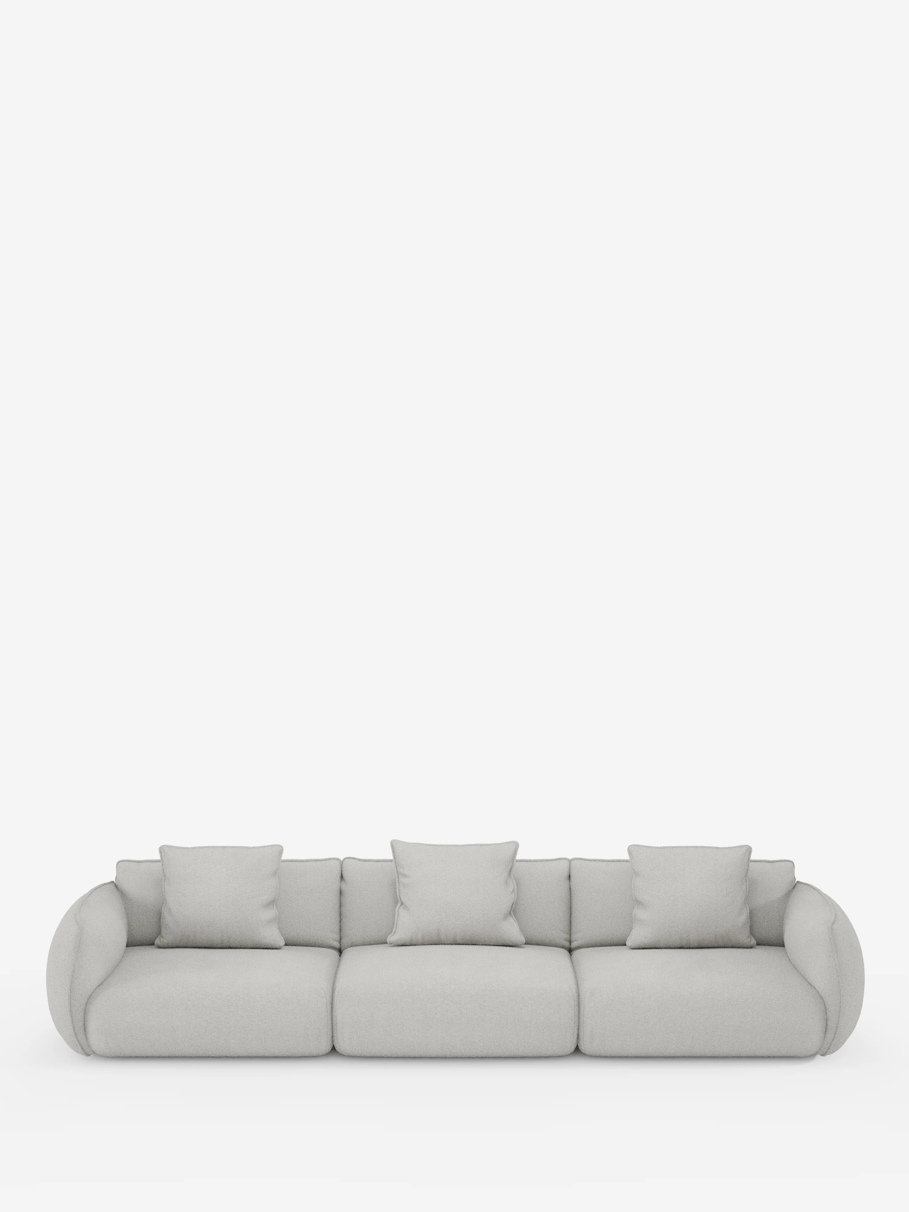 Un divano modulare contemporaneo Nimbus a 3 posti, realizzabile in morbido tessuto antimacchia effetto cotone T33 di Divani.Store, qui raffigurato in grigio chiaro con braccioli arrotondati e bordi morbidi, comprende tre cuscini di seduta e cinque cuscini coordinati ed è presentato su uno sfondo bianco a tinta unita.