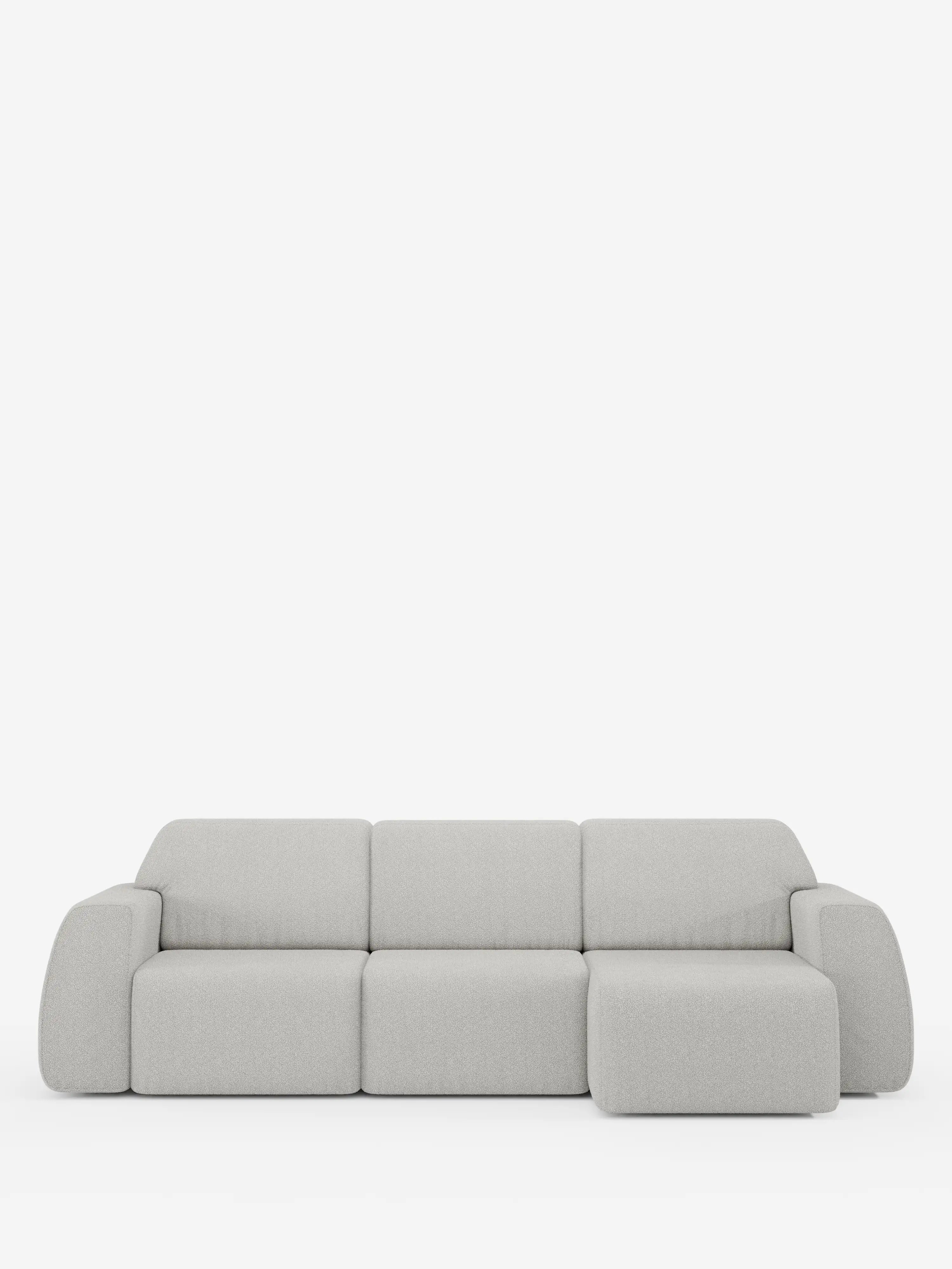 Un divano angolare Orbit contemporaneo, di colore grigio chiaro, con penisola reversibile e tutte le sedute allungabili, rivestito in tessuto smacchiabile effetto cotone T33 di Divani.Store, dotato di tre posti e una chaise longue sul lato destro. Il design minimalista prevede braccioli e schienali imbottiti e spessi, senza gambe a vista, che risaltano su uno sfondo bianco a tinta unita.