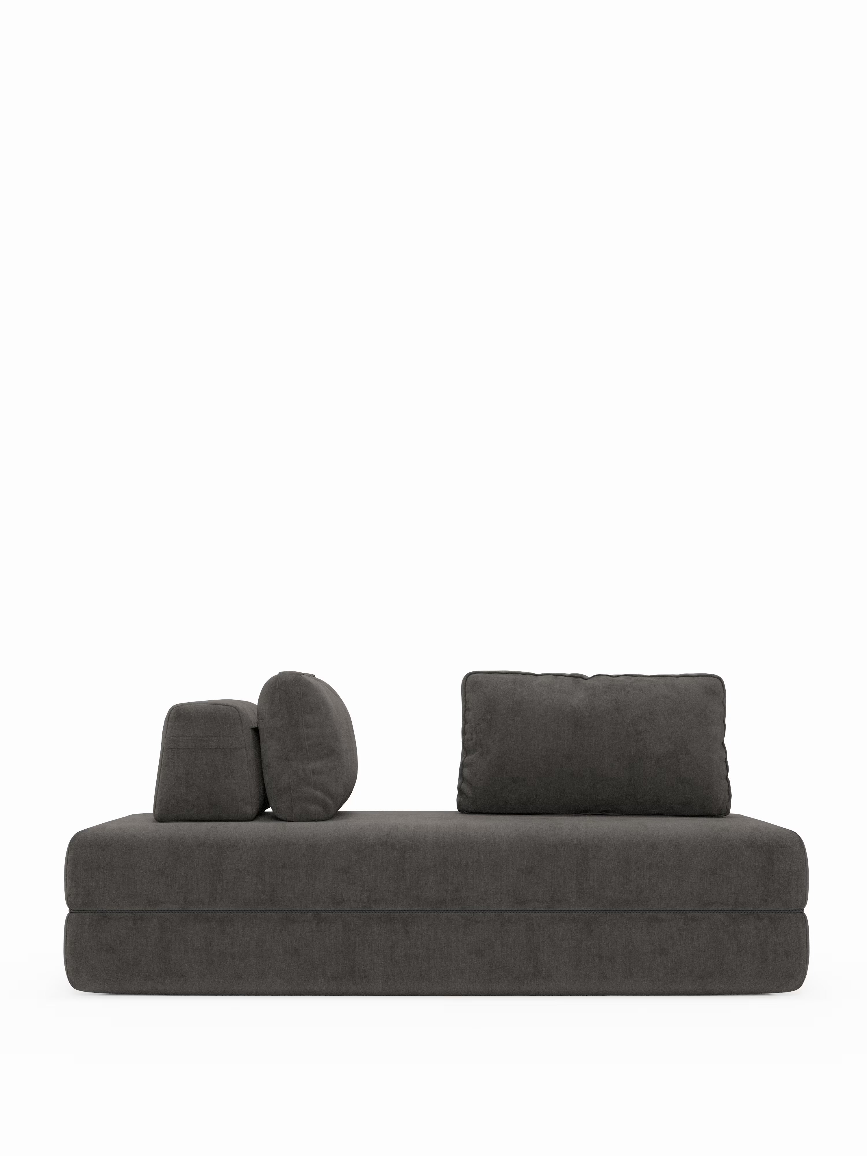 Divano letto matrimoniale minimalista Rift in grigio scuro, disponibile nelle versioni a 2 e 3 posti con schienali mobili, firmato Divani.Store, caratterizzato da una seduta bassa e rettangolare e da tre cuscini rimovibili — uno rettangolare, uno quadrato e uno cilindrico — disposti in modo asimmetrico su uno sfondo bianco a tinta unita. Questo moderno divano trasformabile vanta un design essenziale ed è dotato di un materasso alto 22 cm in schiuma memory T31 per un maggiore comfort e versatilità.