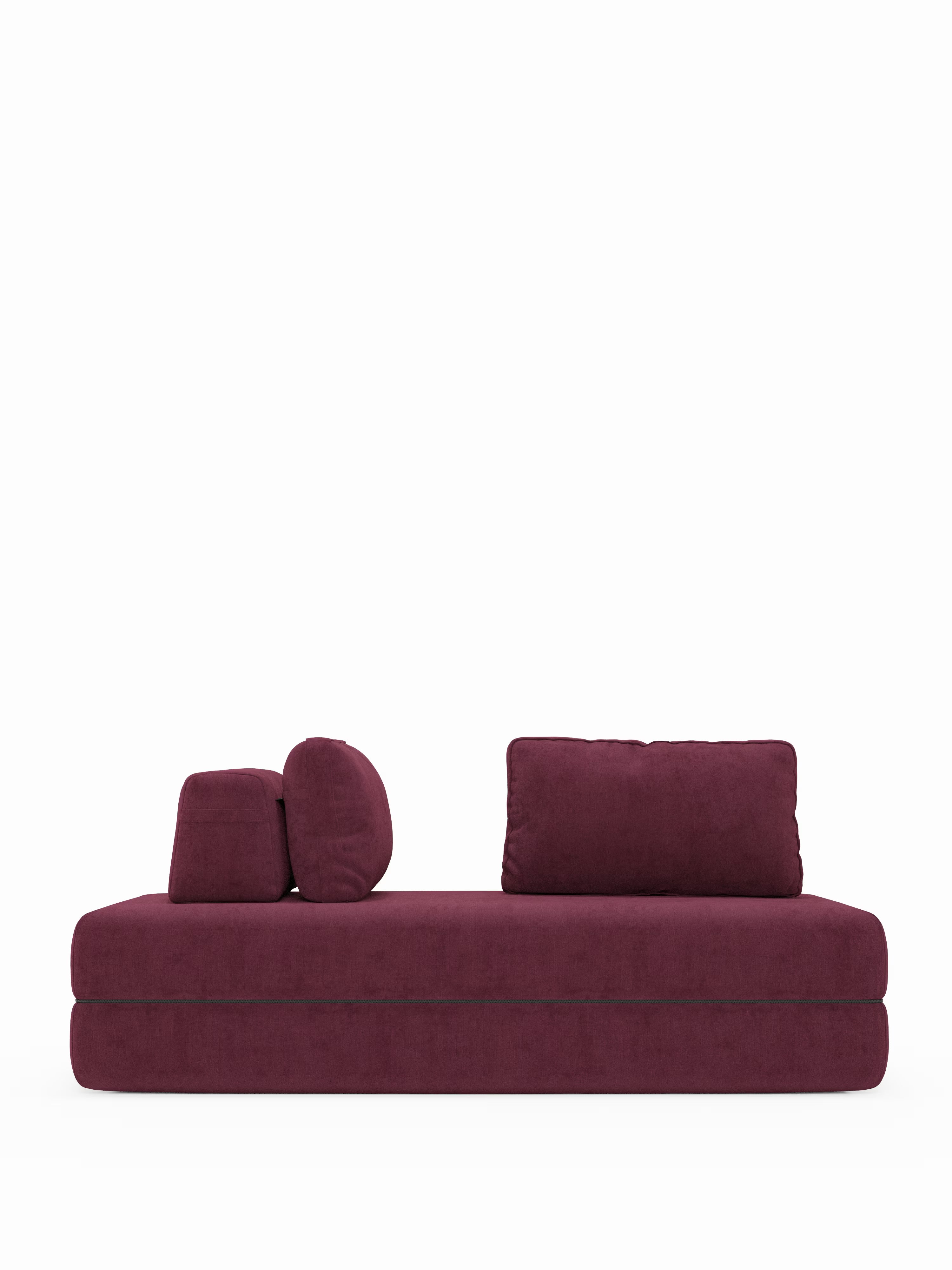 Un moderno divano letto matrimoniale rettangolare Rift a 2 e 3 posti con schienali mobili di Divani.Store, rivestito in tessuto bordeaux e dotato di due cuscini rettangolari e due rotondi coordinati, oltre che di un comodo materasso in memory foam alto 22 cm nella versione T31, è posizionato su uno sfondo bianco a tinta unita.