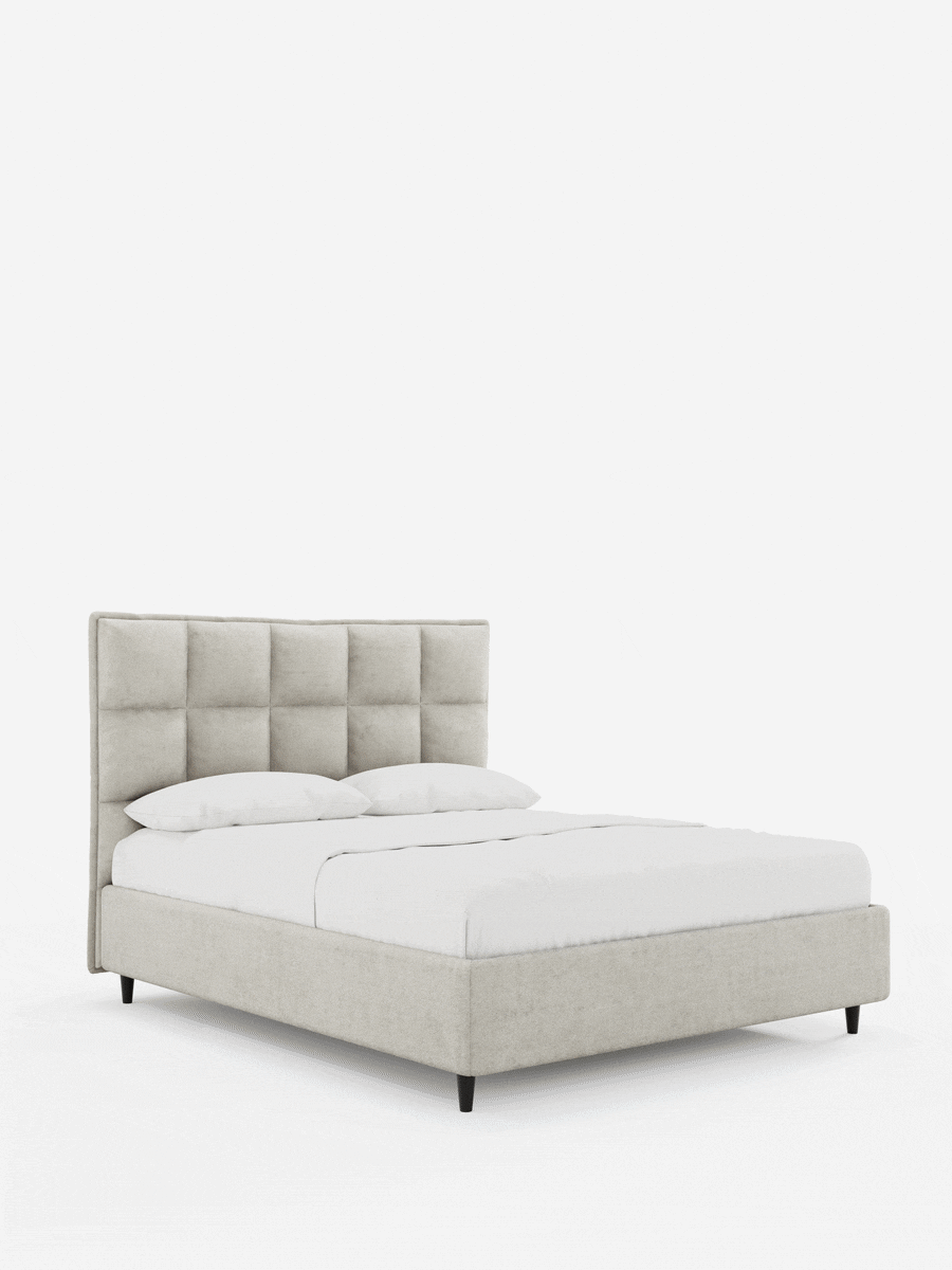 Il letto imbottito AURO con contenitore e testiera alta capitonné in ciniglia Oeko-Tex® è un letto imbottito beige con una testiera alta capitonné, biancheria da letto bianca e quattro gambe affusolate scure su sfondo bianco.