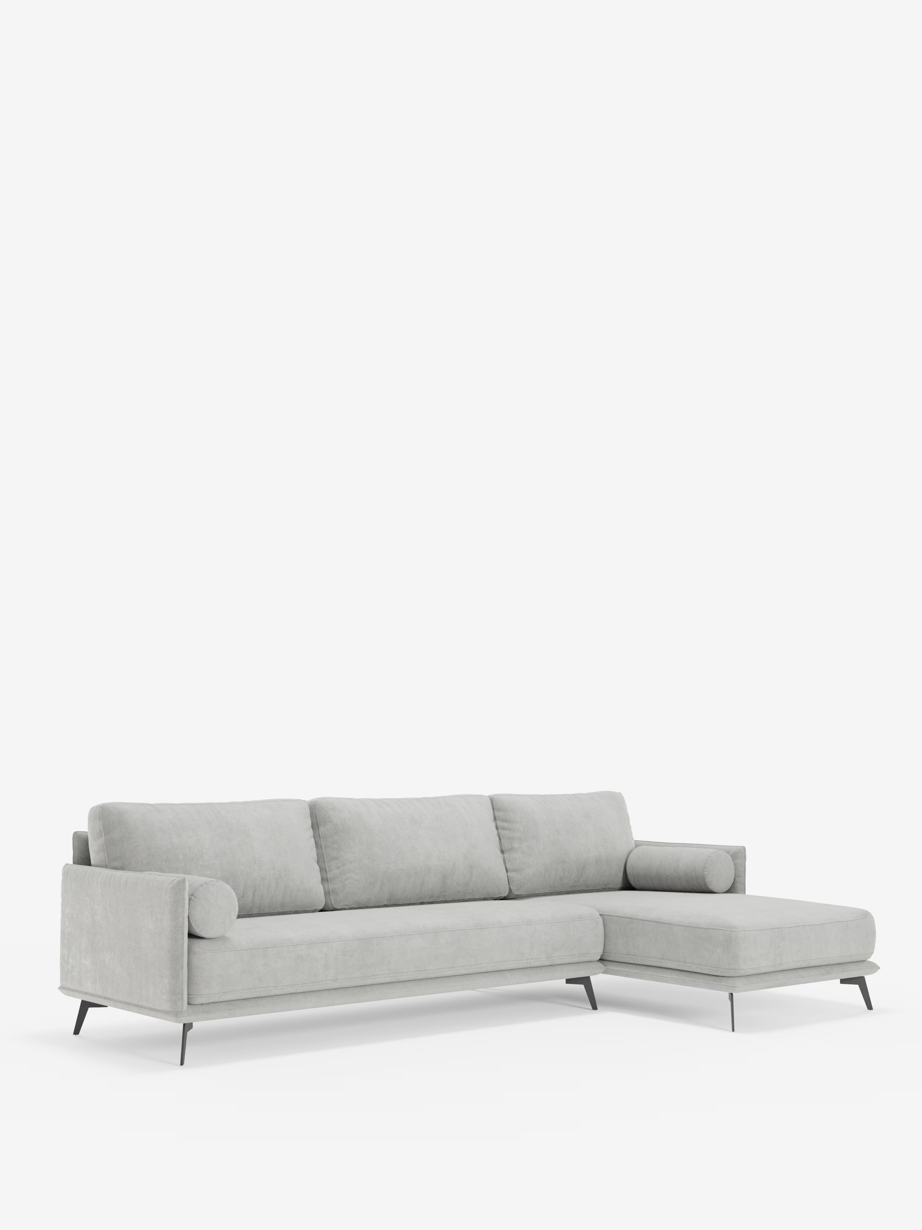 Il divano angolare moderno con penisola “Basalto” di Divani.Store è un divano componibile di colore grigio chiaro, dalle linee pulite, con una base in metallo sottile, tre cuscini dello schienale e una chaise longue orientata a destra. Questo elegante divano Made in Italy presenta braccioli cilindrici e morbidi cuscini in piuma rivestiti in tessuto T31 antimacchia, che risaltano sullo sfondo bianco.