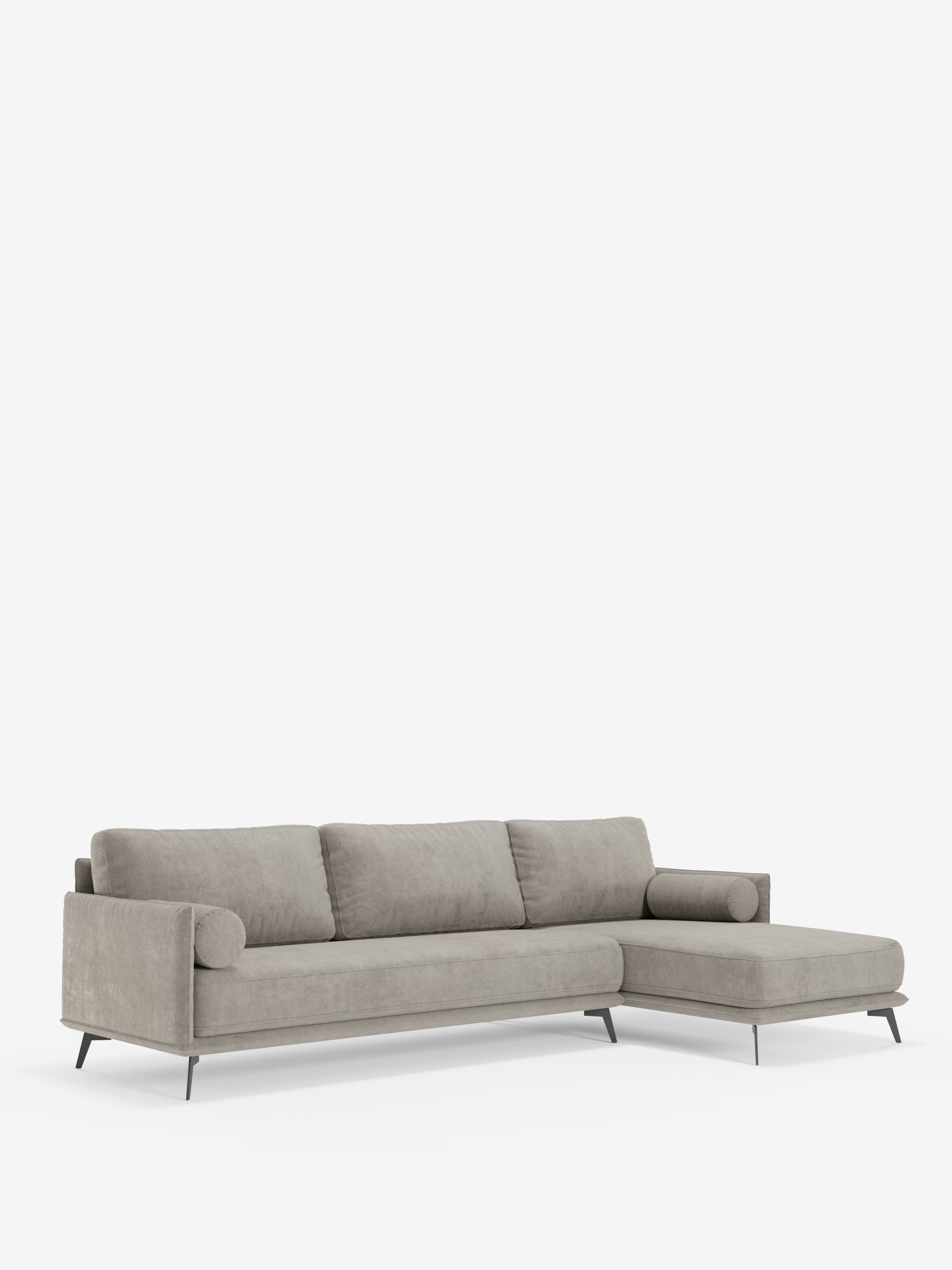 Il divano moderno angolare con penisola “Basalto” di Divani.Store presenta un design moderno in grigio chiaro, con tre cuscini di seduta, braccioli bassi e arrotondati e sottili gambe in metallo nero. Il lato destro si estende in una chaise longue, il tutto su uno sfondo bianco a tinta unita. Rivestito in tessuto smacchiabile T31 con cuscini in piuma e una robusta base in metallo, questo divano dalle linee eleganti incarna lo stile italiano contemporaneo.