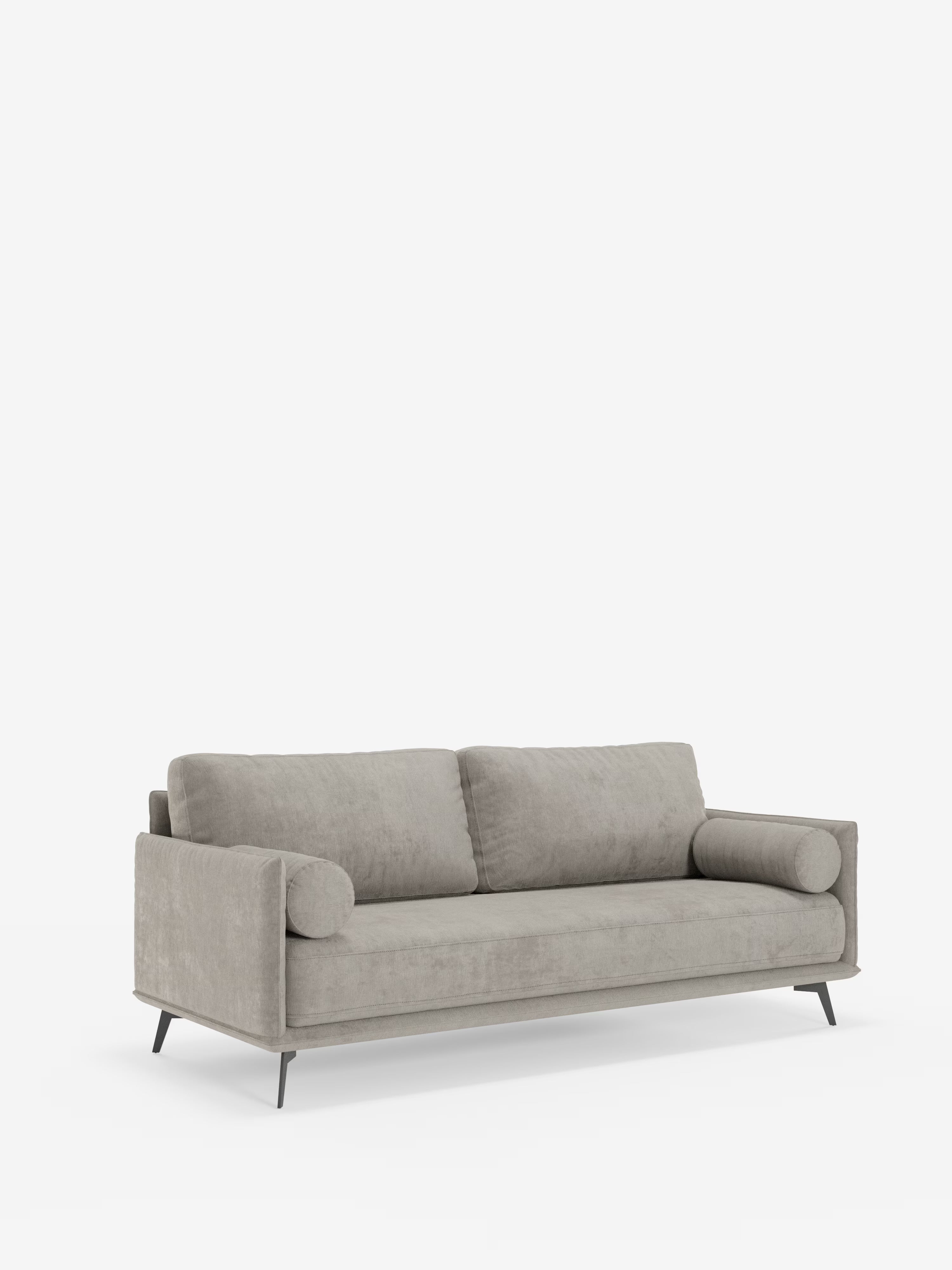 Un divano lineare Basalto di Divani.Store in grigio chiaro contemporaneo, caratterizzato da un unico cuscino di seduta in tessuto smacchiabile T31, un'elegante base in metallo nero, linee pulite e minimaliste, due cuscini rettangolari per lo schienale e due cuscini cilindrici, il tutto su uno sfondo bianco.