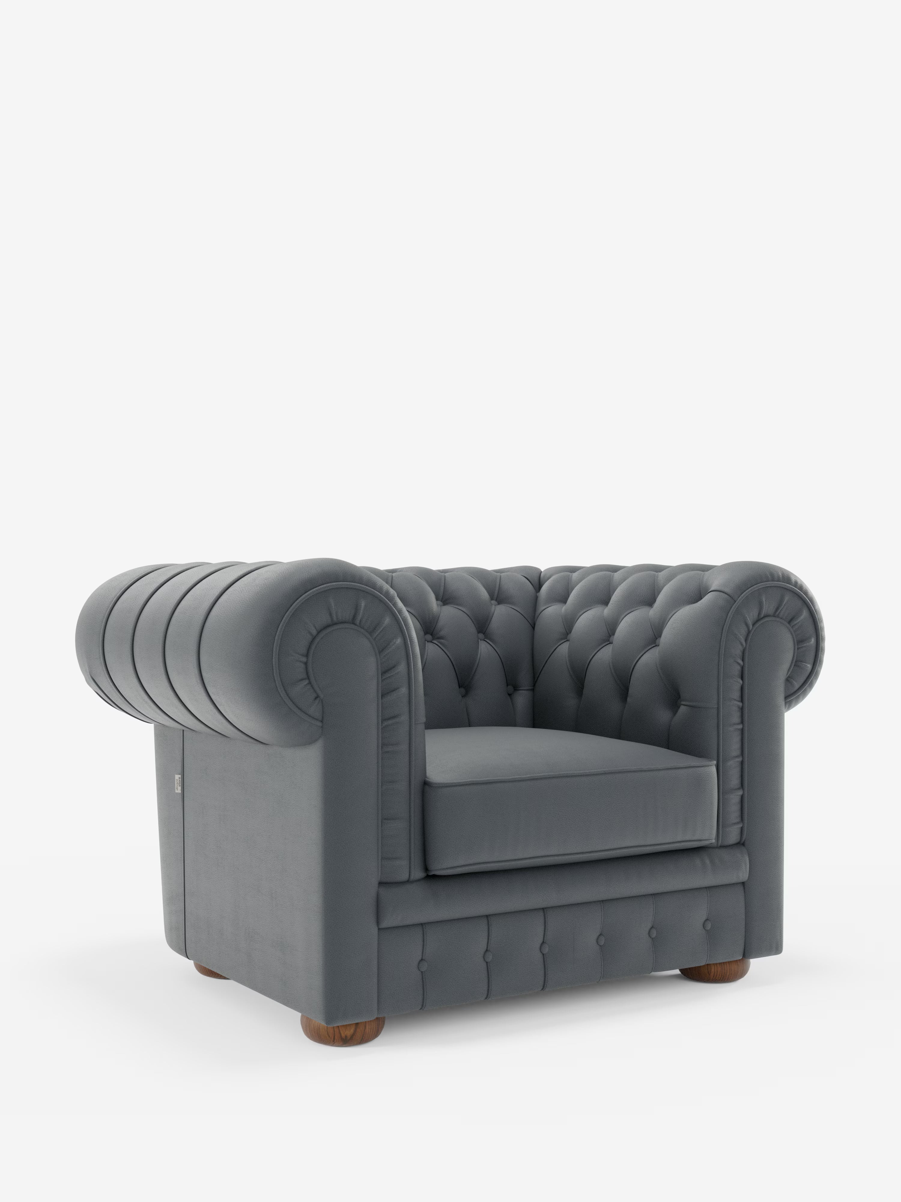 Una poltrona Chester grigia in vera pelle spessorata con capitonné artigianale di Divani.Store, caratterizzata da rivestimento capitonné, braccioli arrotondati, bottoni profondi e piedini rotondi in legno, su sfondo bianco.