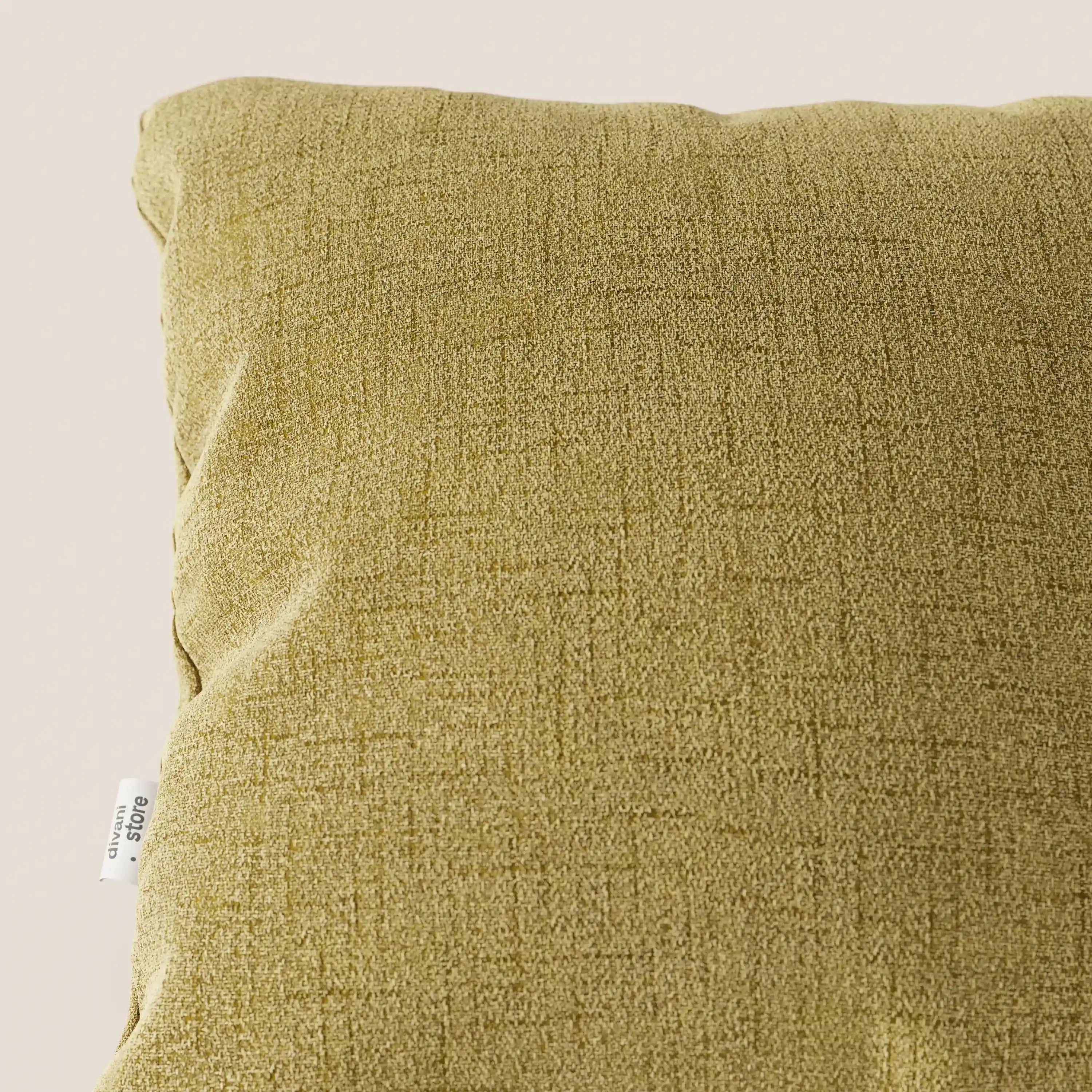 Primo piano del cuscino Felis di Divani.Store in T03 giallo, realizzato in morbido tessuto idrorepellente con una sottile fantasia a scacchi. Sullo sfondo chiaro sono visibili solo la parte in alto a sinistra e una piccola etichetta bianca.